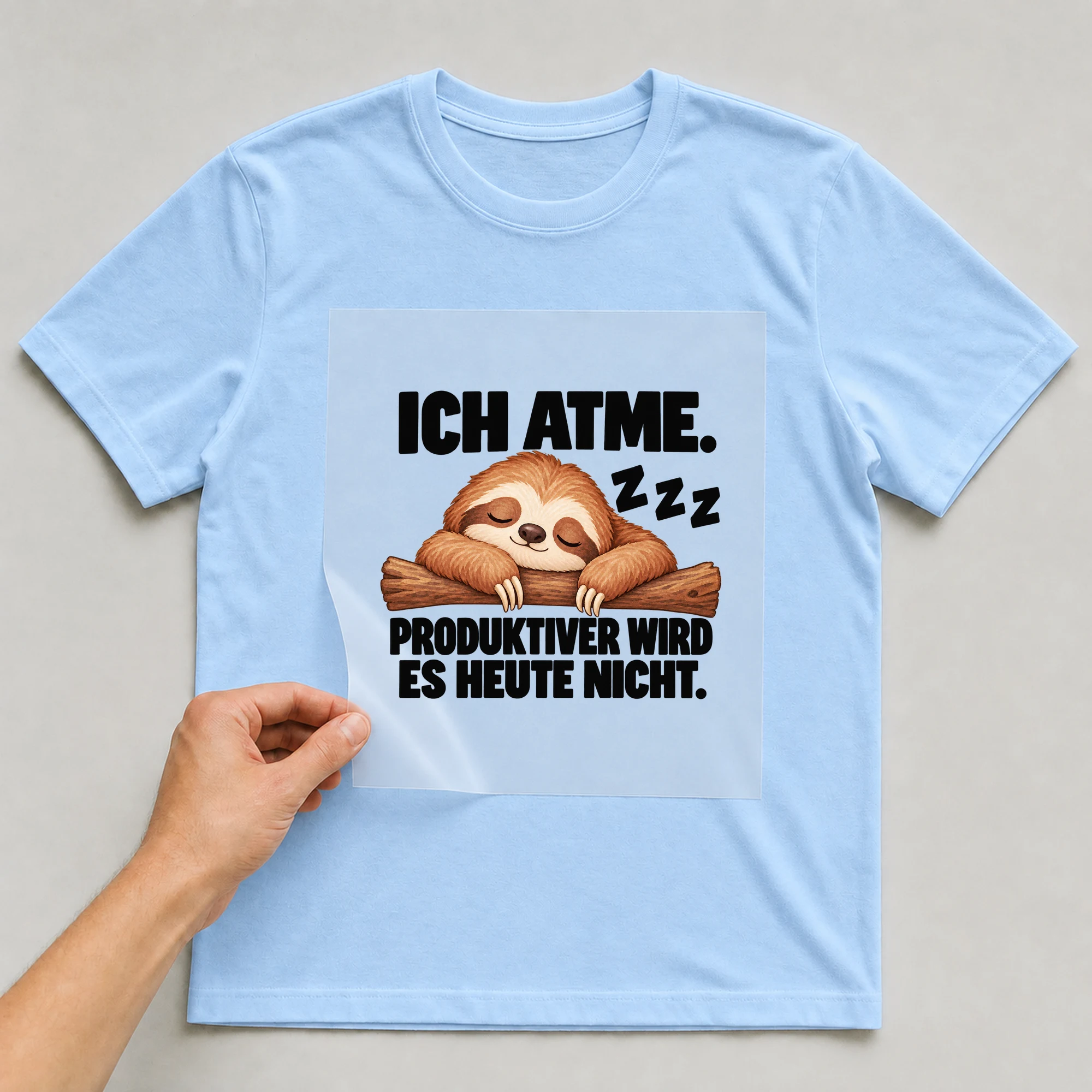 Bügelbild „Ich atme. Z z z produktiver wird es heute nicht.“ auf babyblauem T-Shirt, Folie wird aufgelegt