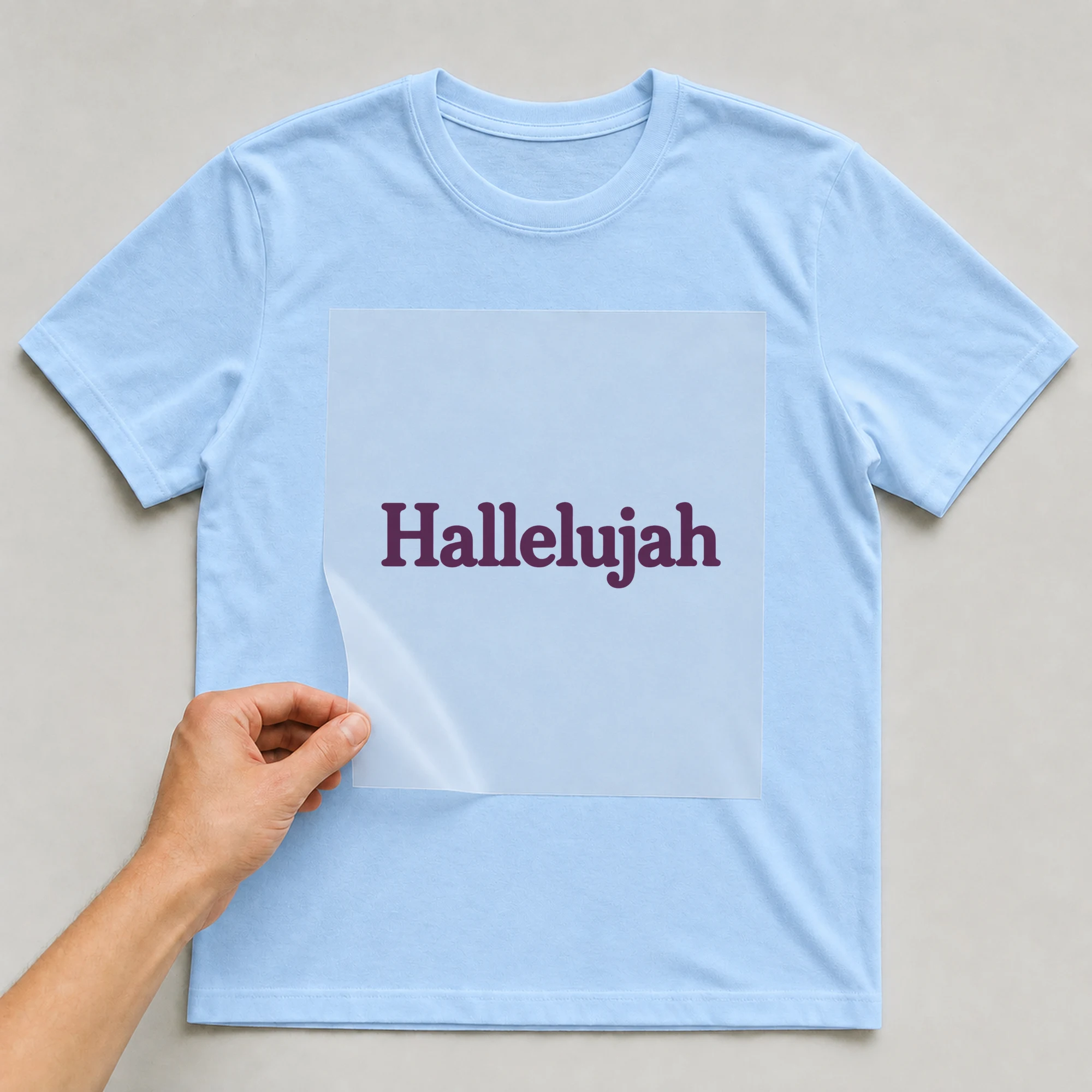 Bügelbild „Hallelujah“ auf babyblauem T-Shirt, Folie wird aufgelegt