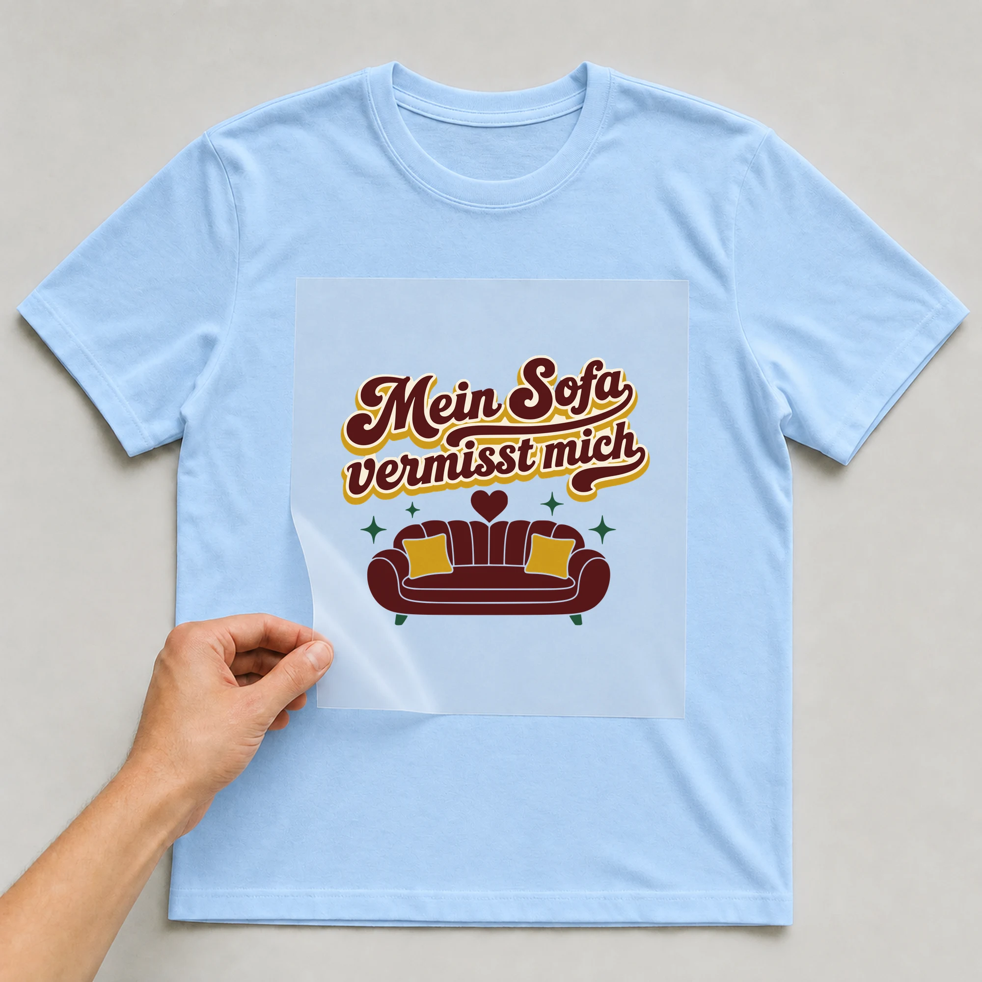 Bügelbild Mein Sofa vermisst mich auf hellblauem T-Shirt, Folie wird aufgelegt