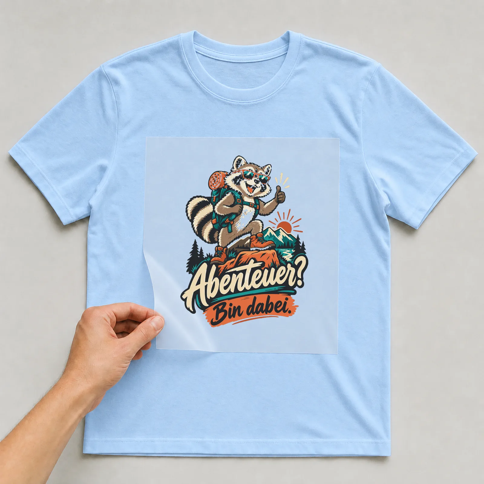Bügelbild Abenteuer? Bin dabei. auf hellblauem T-Shirt, Folie wird aufgelegt
