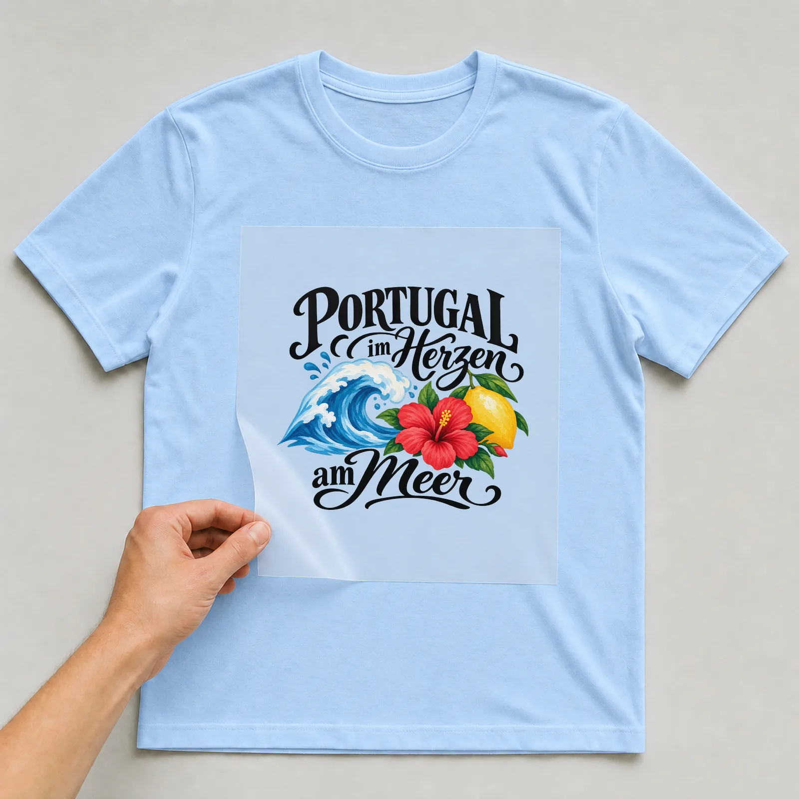 Bügelbild „PORTUGAL im Herzen am Meer“ auf hellblauem T-Shirt, Folie wird aufgelegt