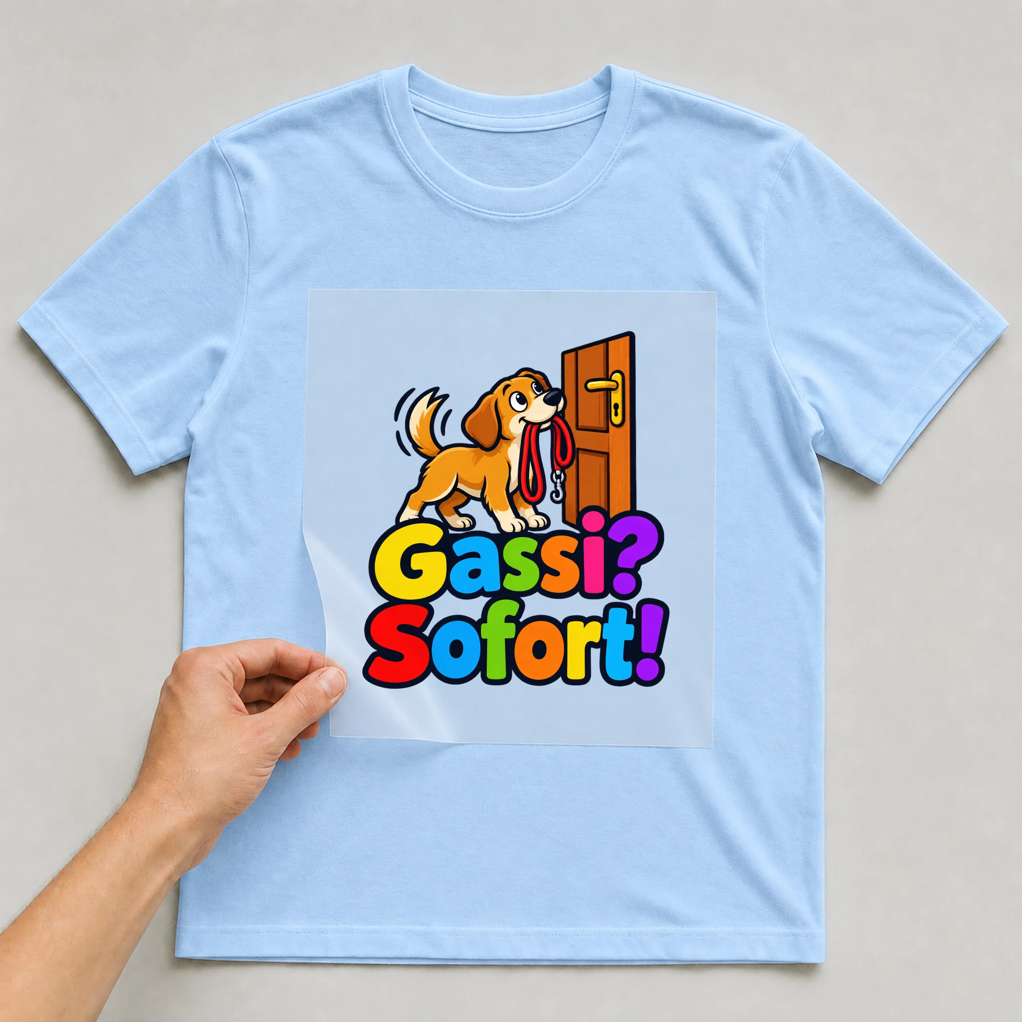 Bügelbild „Gassi? Sofort!“ auf babyblauem T-Shirt, Folie wird aufgelegt