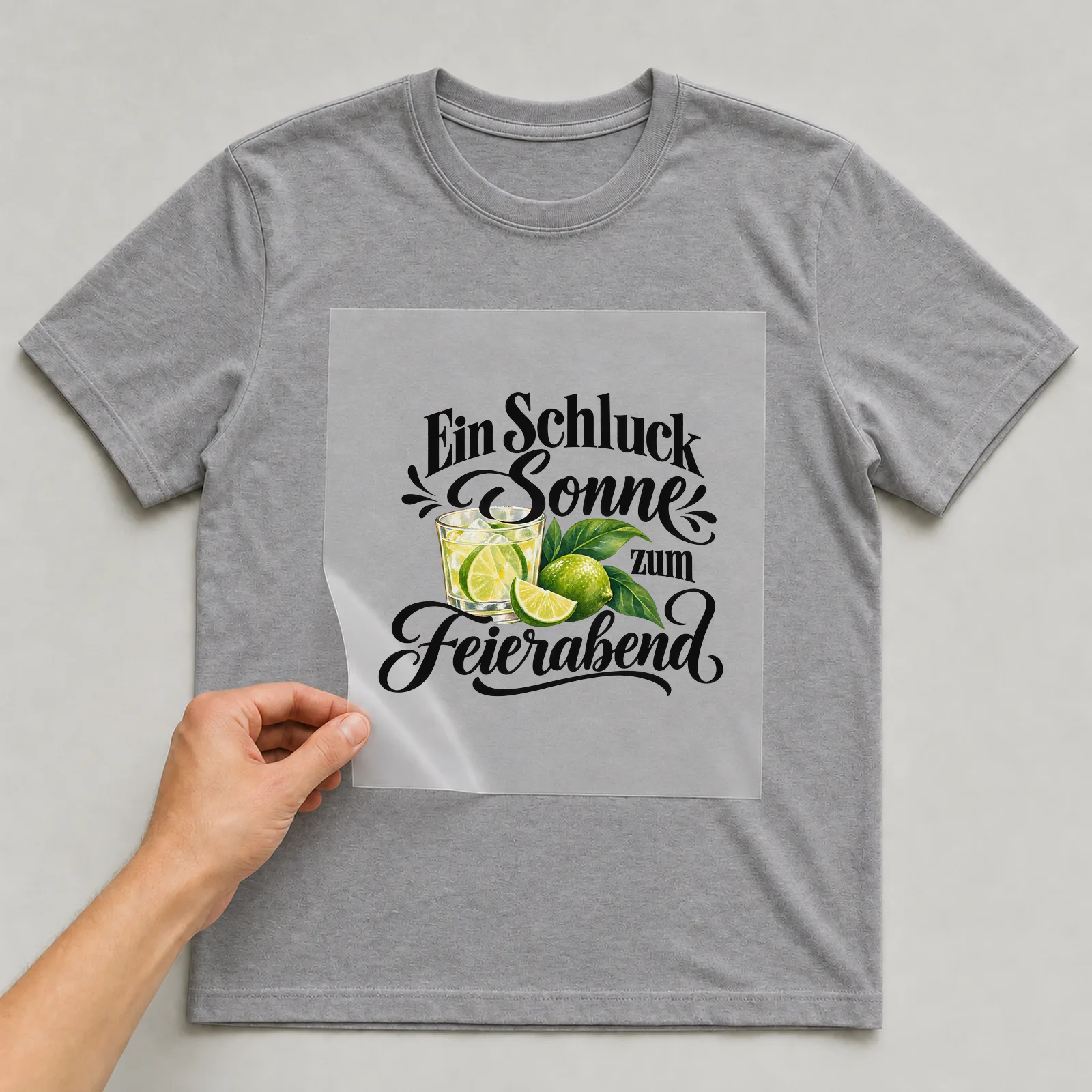 Bügelbild „Ein Schluck Sonne zum Feierabend“ auf grauem T-Shirt, Folie wird aufgelegt