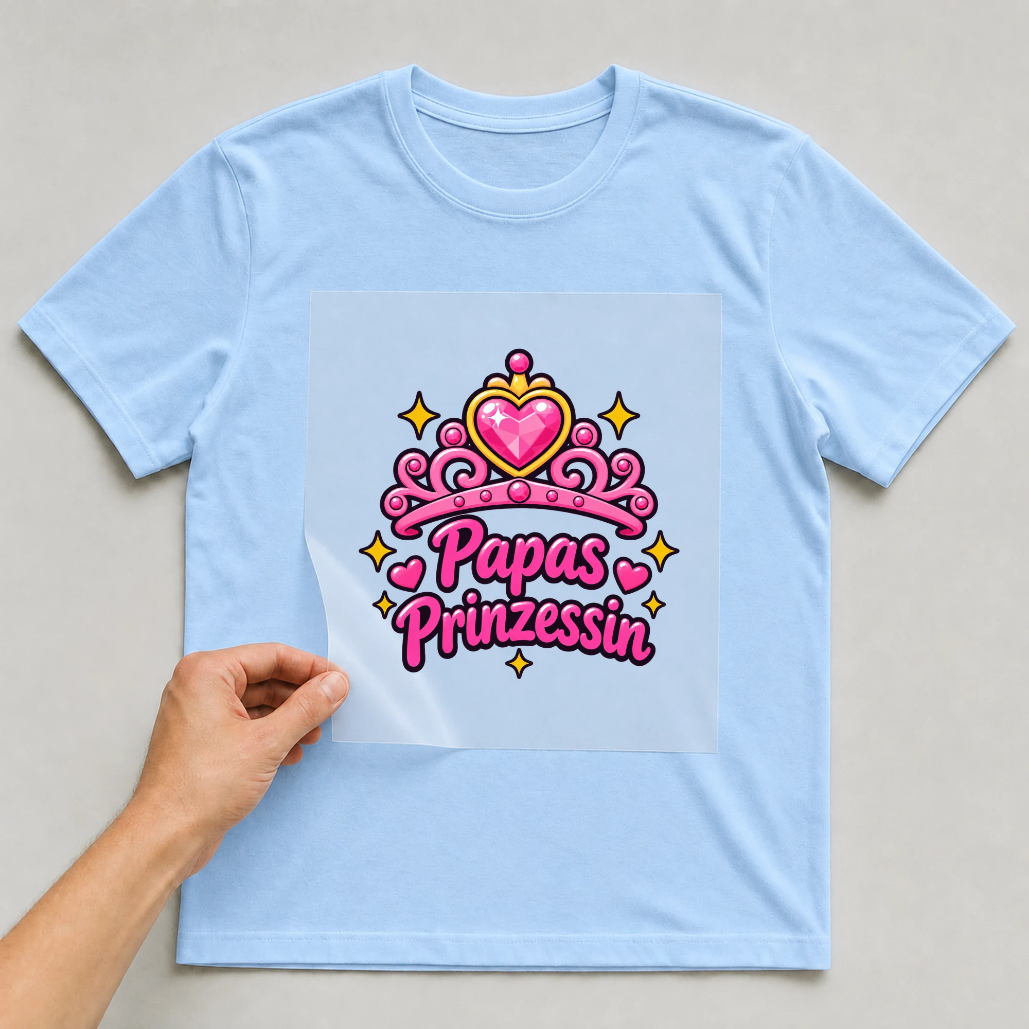 Bügelbild „Papas Prinzessin“ auf babyblauem T-Shirt, Folie wird aufgelegt