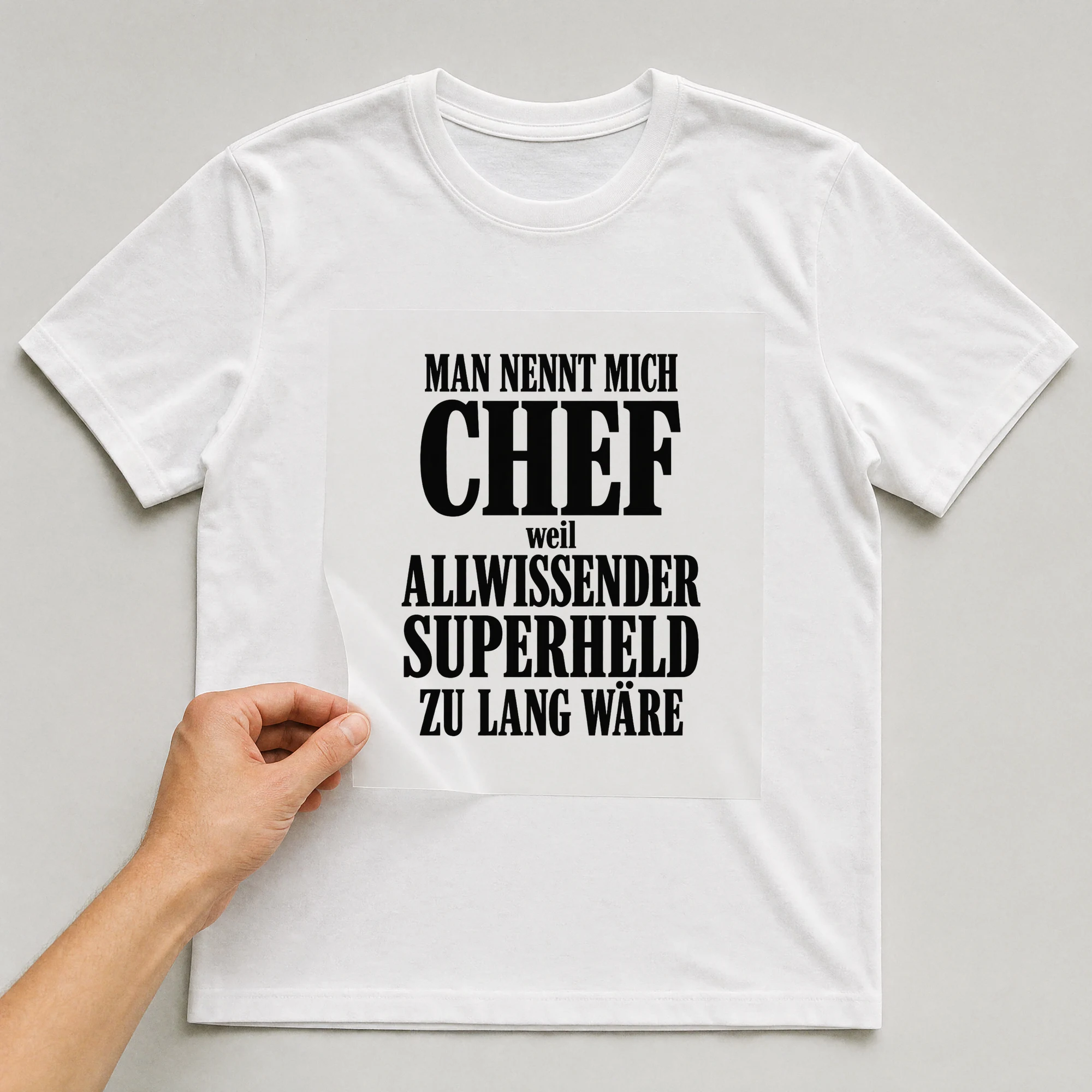 Bügelbild „Man nennt mich Chef, weil Allwissender Superheld zu lang wäre“ auf weißem T-Shirt, Folie wird aufgelegt