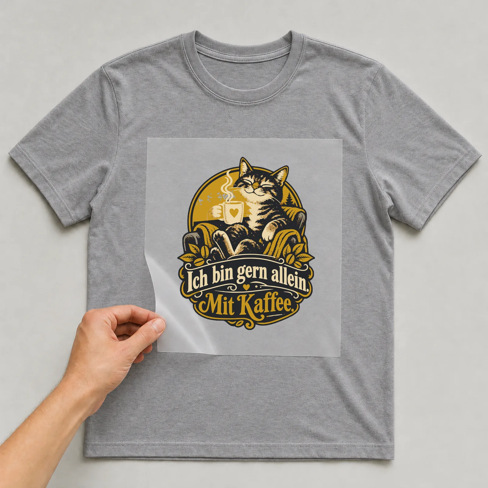 Bügelbild Ich bin gern allein. Mit Kaffee. auf grauem T-Shirt, Folie wird aufgelegt