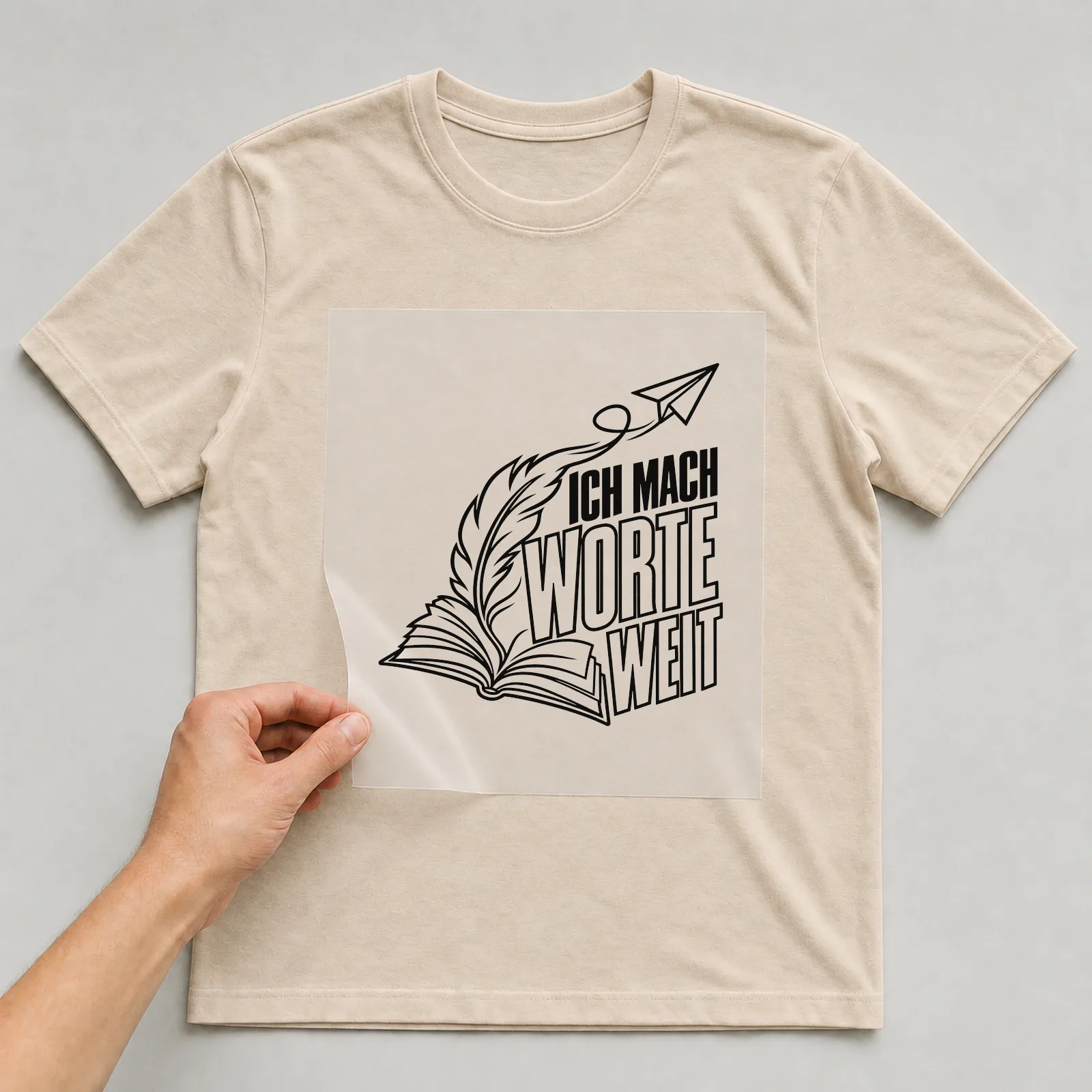 Bügelbild „Ich mach Worte weit“ auf beigem T-Shirt, Folie wird aufgelegt