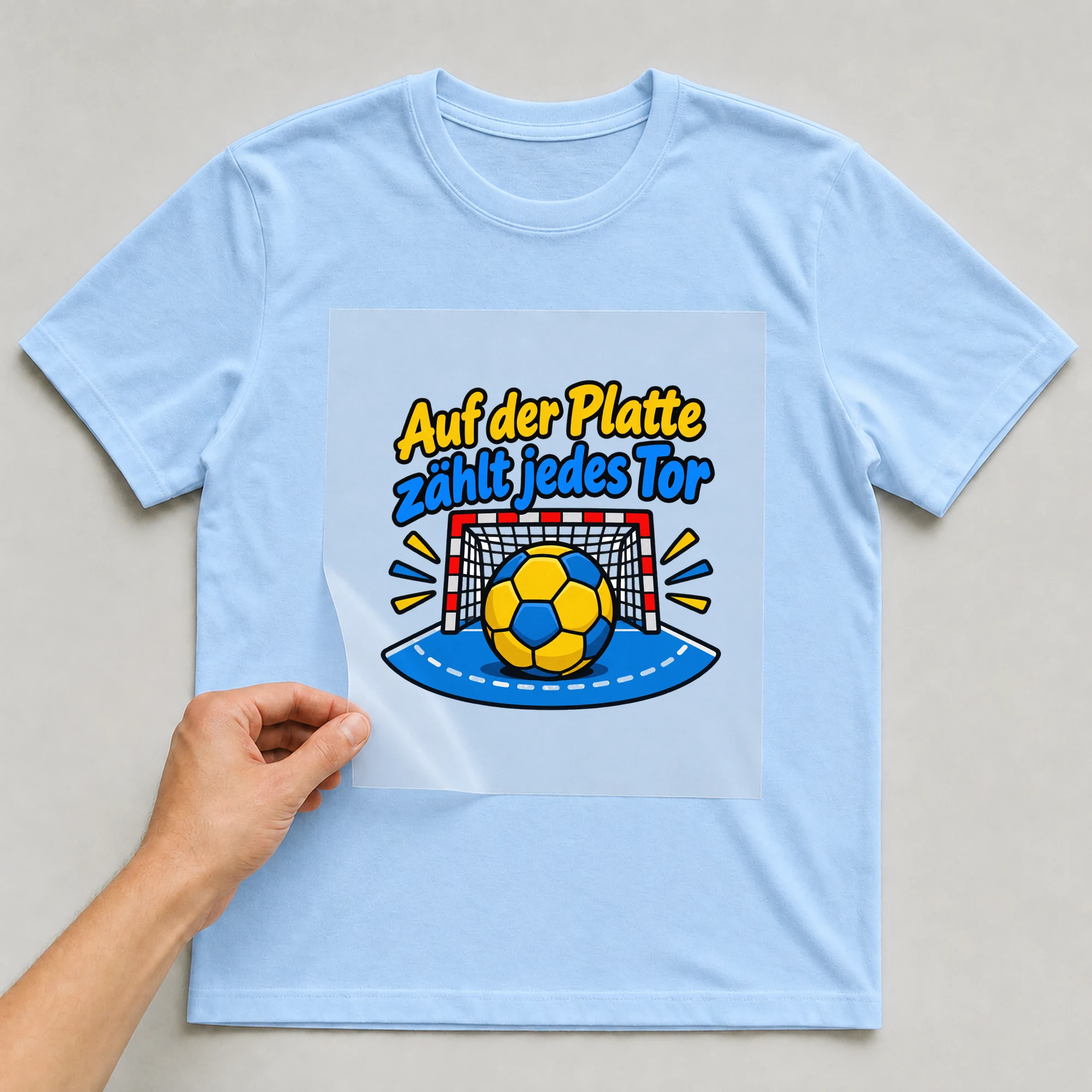 Bügelbild „Auf der Platte zählt jedes Tor“ auf babyblauem T-Shirt, Folie wird aufgelegt