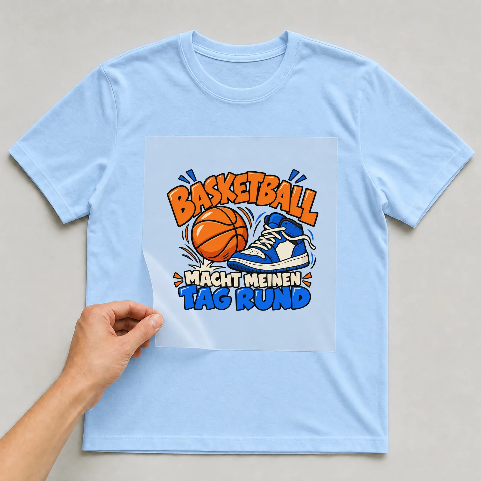 Bügelbild „Basketball macht meinen Tag rund“ auf hellblauem T-Shirt, Folie wird aufgelegt