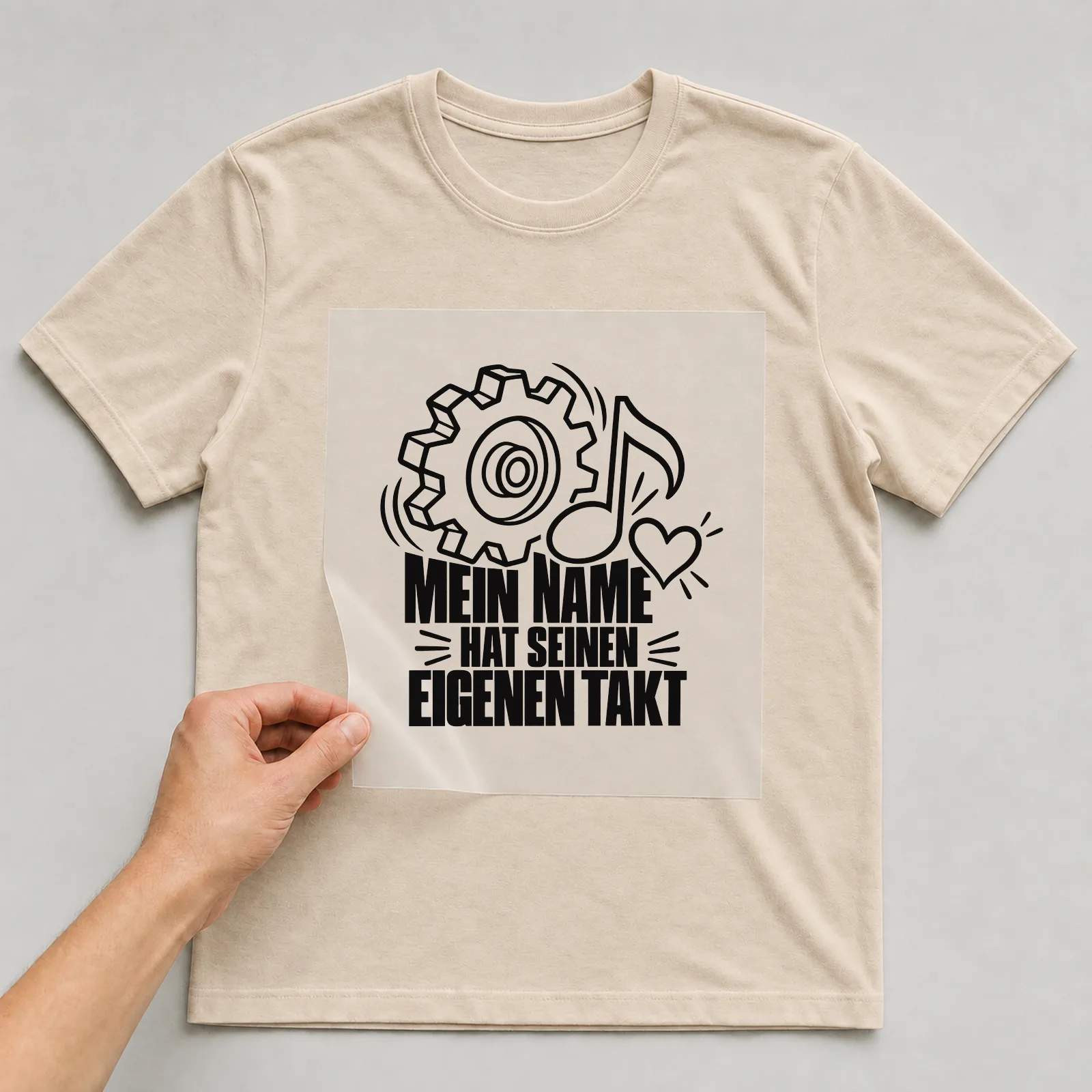 Bügelbild „Mein Name hat seinen eigenen Takt“ auf beigem T-Shirt, Folie wird aufgelegt