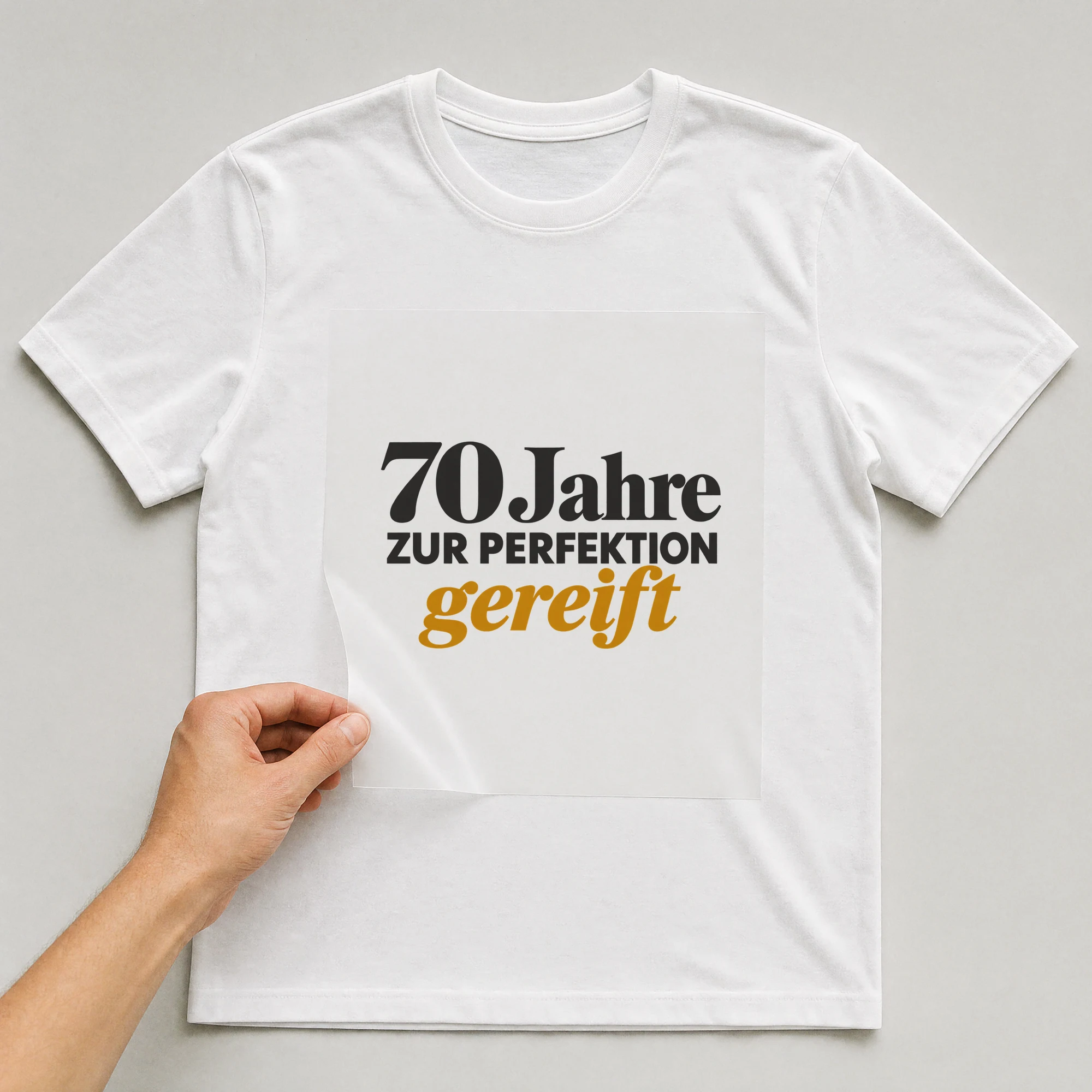 Bügelbild „70 Jahre zur Perfektion gereift“ auf weißem T-Shirt, Folie wird aufgelegt