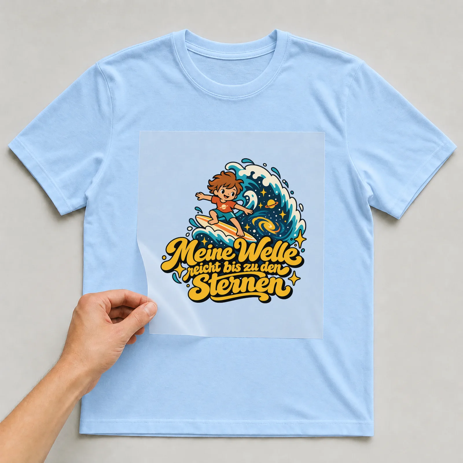 Bügelbild „Meine Welle reicht bis zu den Sternen“ auf hellblauem T-Shirt, Folie wird aufgelegt
