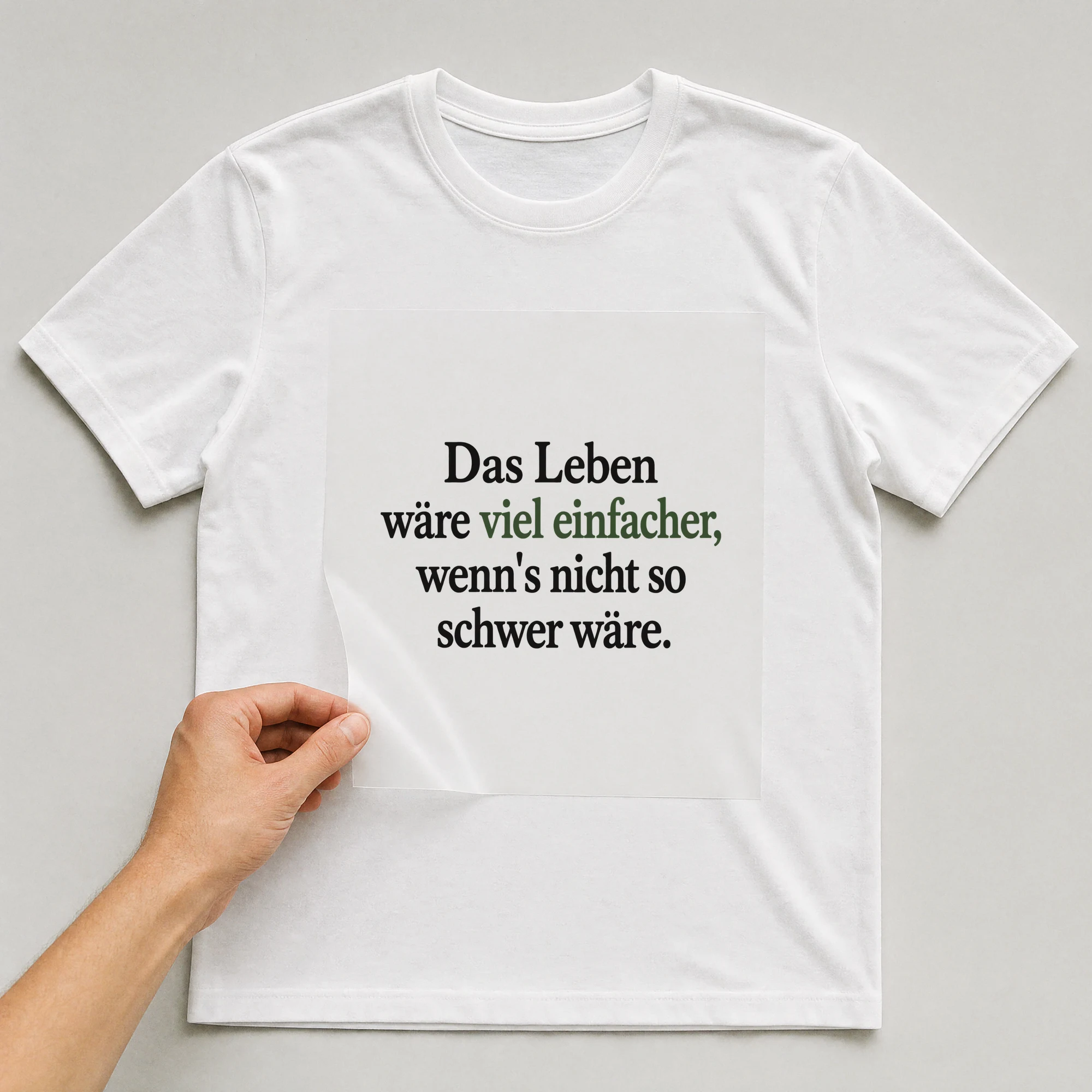 Bügelbild „Das Leben wäre viel einfacher, wenn's nicht so schwer wäre.“ auf weißem T-Shirt, Folie wird aufgelegt
