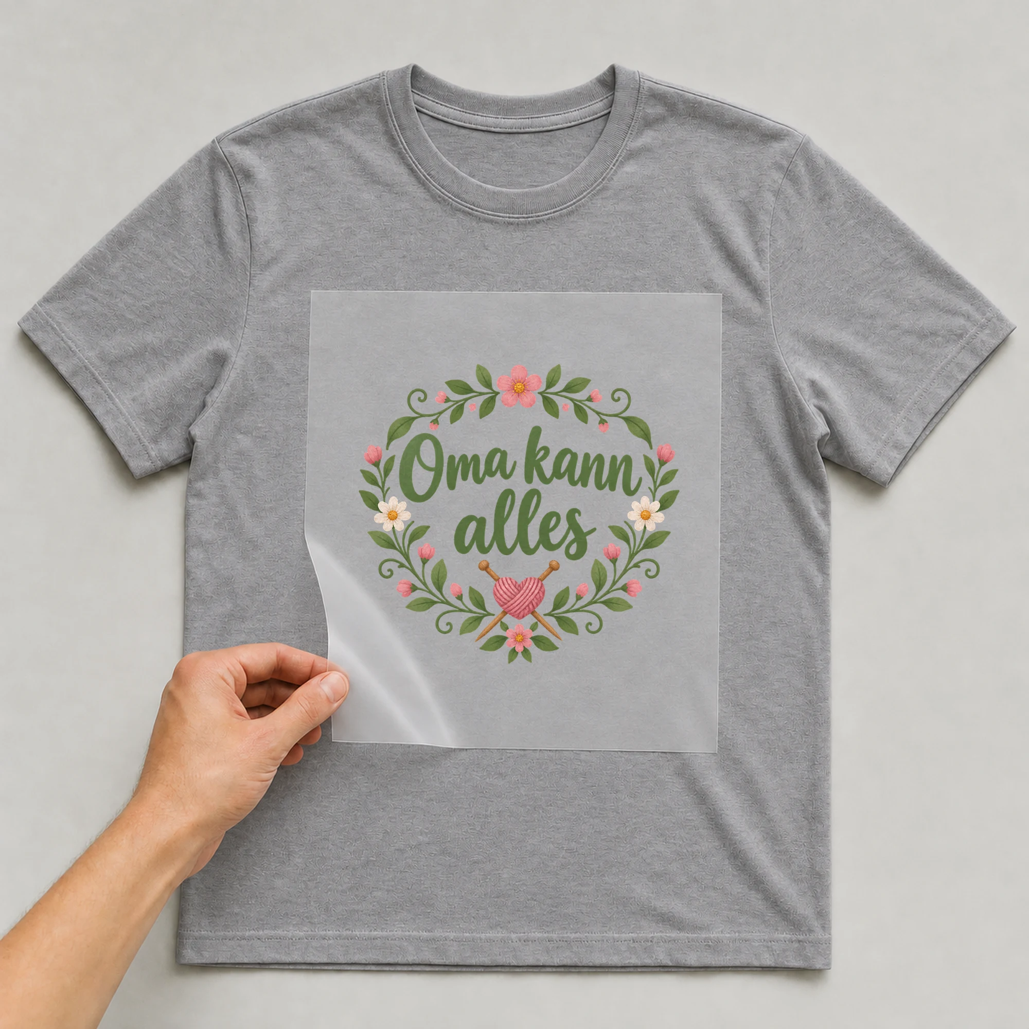 Bügelbild „Oma kann alles“ auf grauem T-Shirt, Folie wird aufgelegt