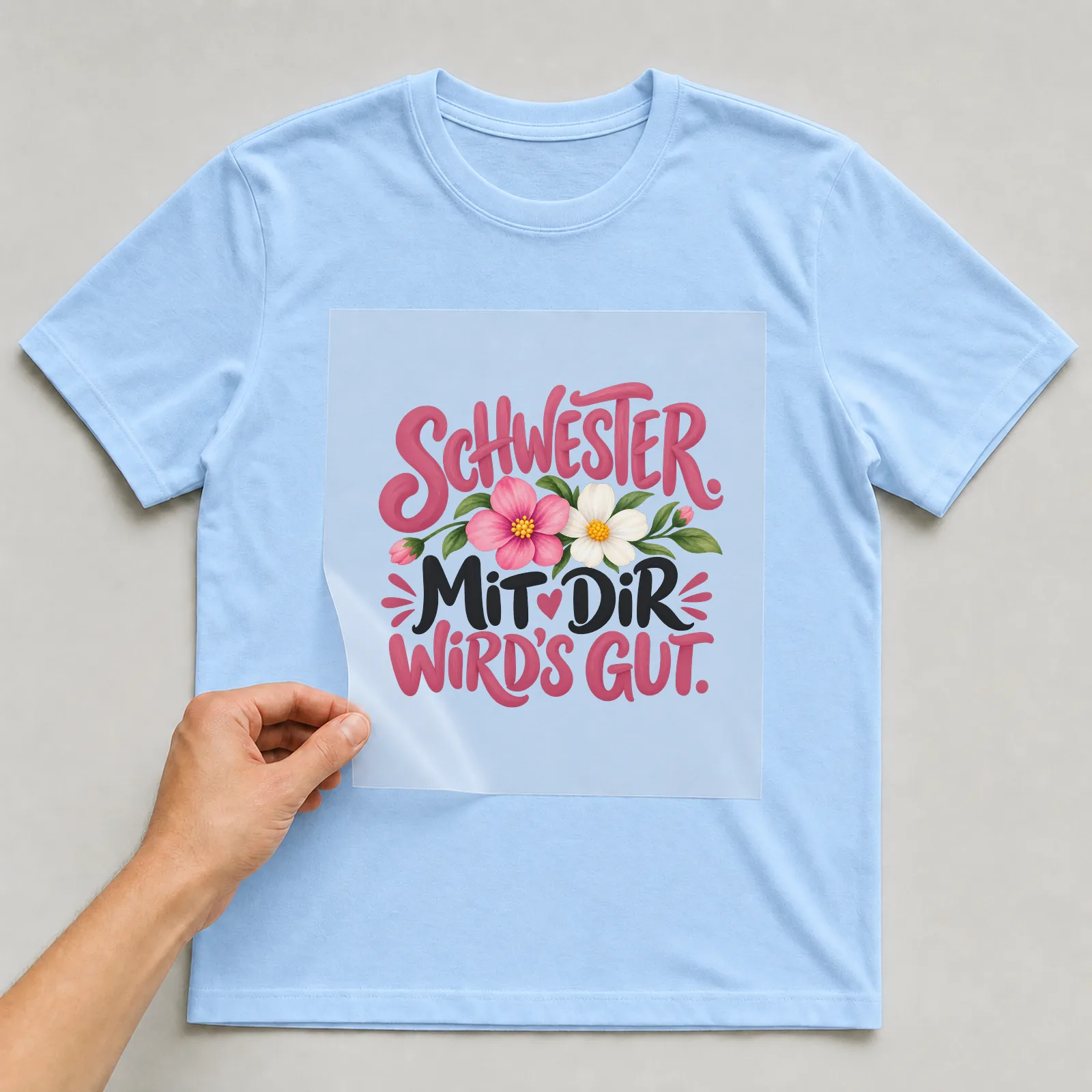 Bügelbild „Schwester. Mit dir wird's gut.“ auf hellblauem T-Shirt, Folie wird aufgelegt