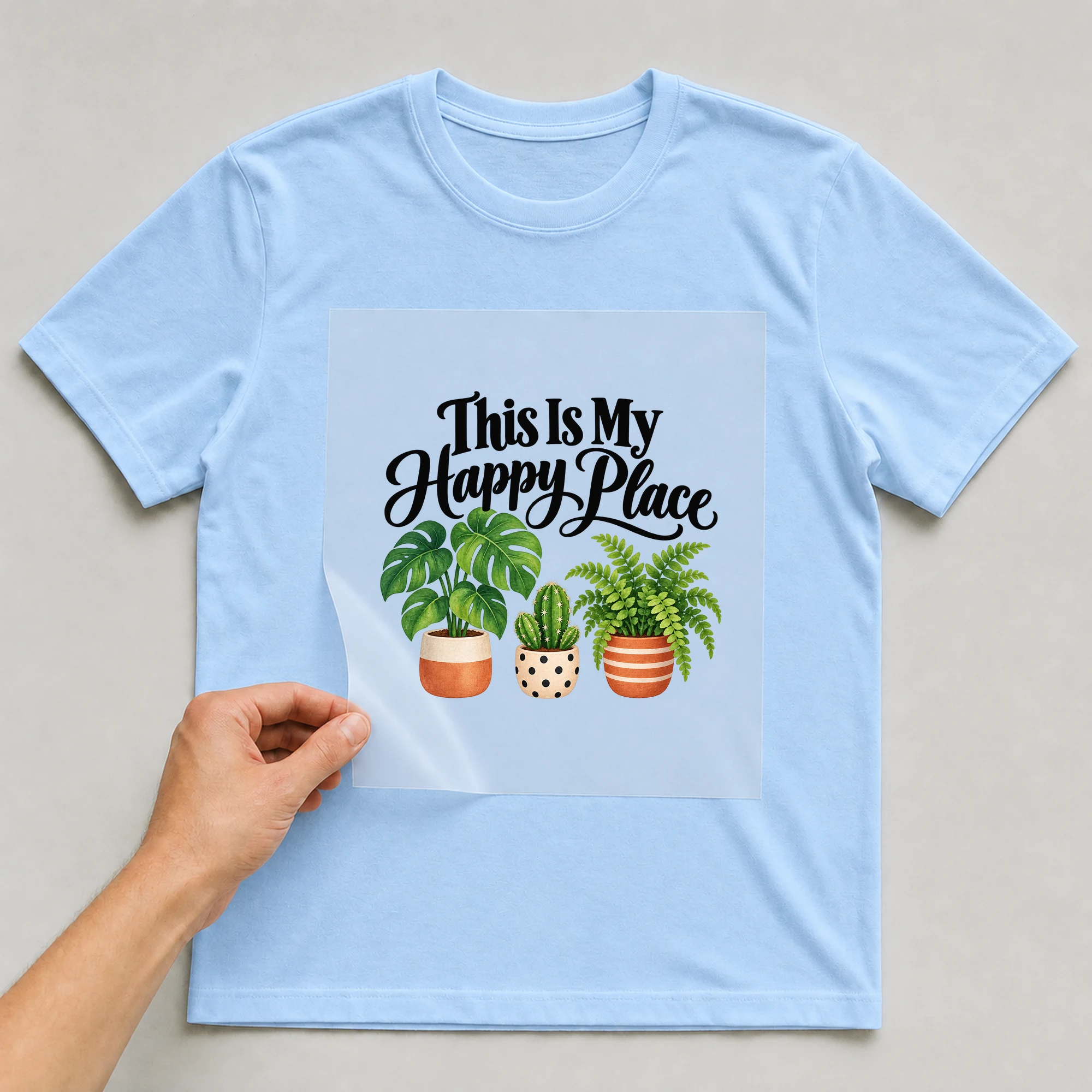 Bügelbild „This Is My Happy Place“ auf babyblauem T-Shirt, Folie wird aufgelegt