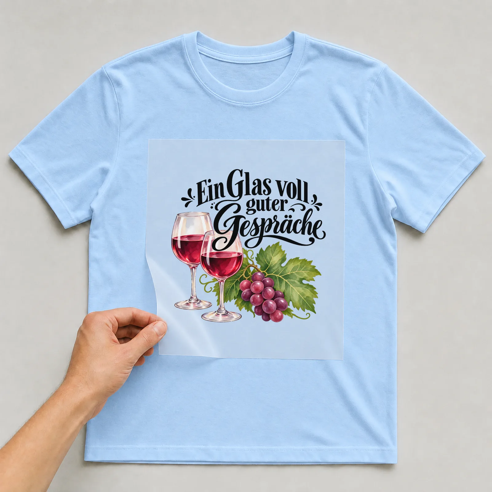 Bügelbild „Ein Glas voll guter Gespräche“ auf hellblauem T-Shirt, Folie wird aufgelegt