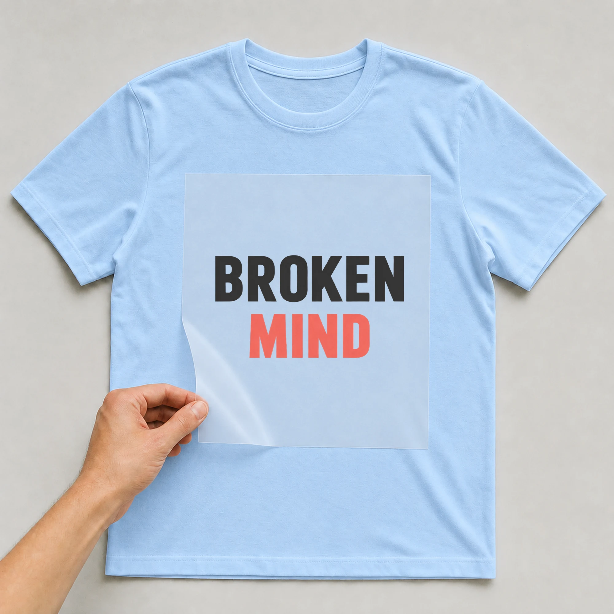 Bügelbild „BROKEN MIND“ auf babyblauem T-Shirt, Folie wird aufgelegt