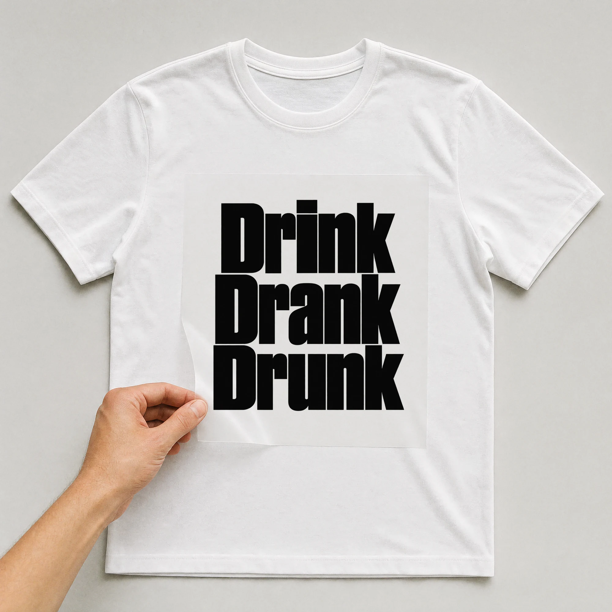 Bügelbild „Drink Drank Drunk“ auf weißem T-Shirt, Folie wird aufgelegt