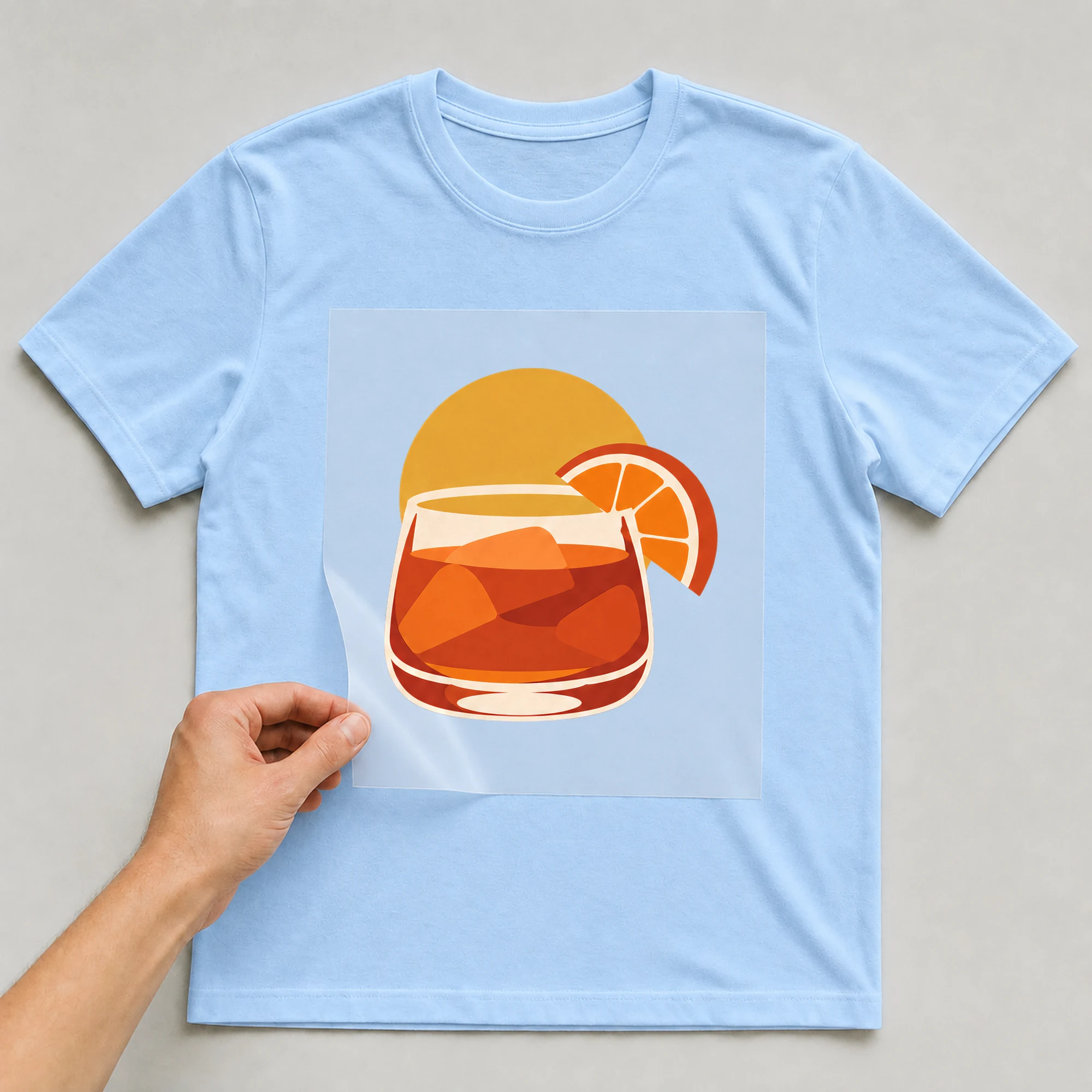 Bügelbild „Apero Sonnenuntergang“ auf babyblauem T-Shirt, Folie wird aufgelegt