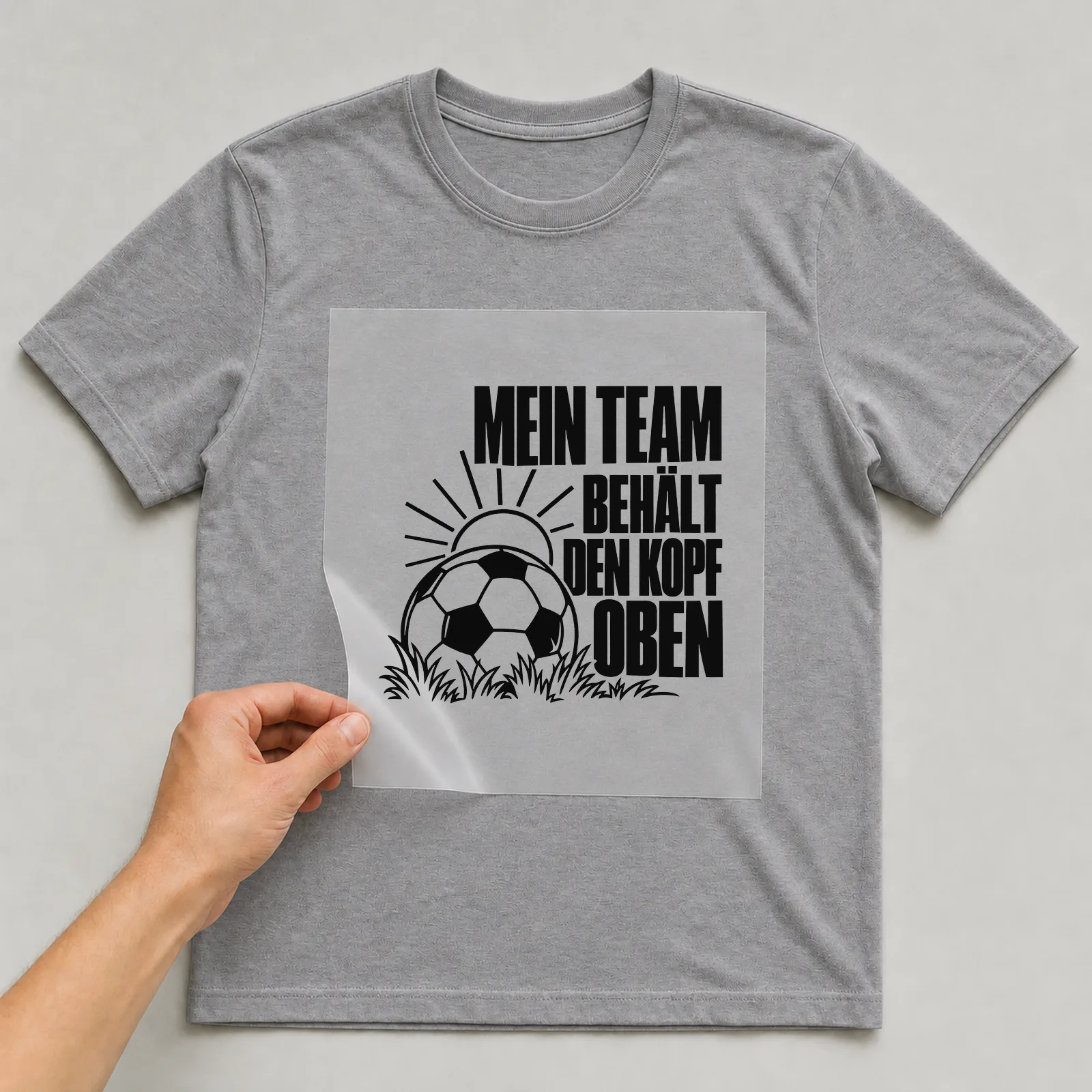 Bügelbild „Mein Team behält den Kopf oben“ auf grauem T-Shirt, Folie wird aufgelegt