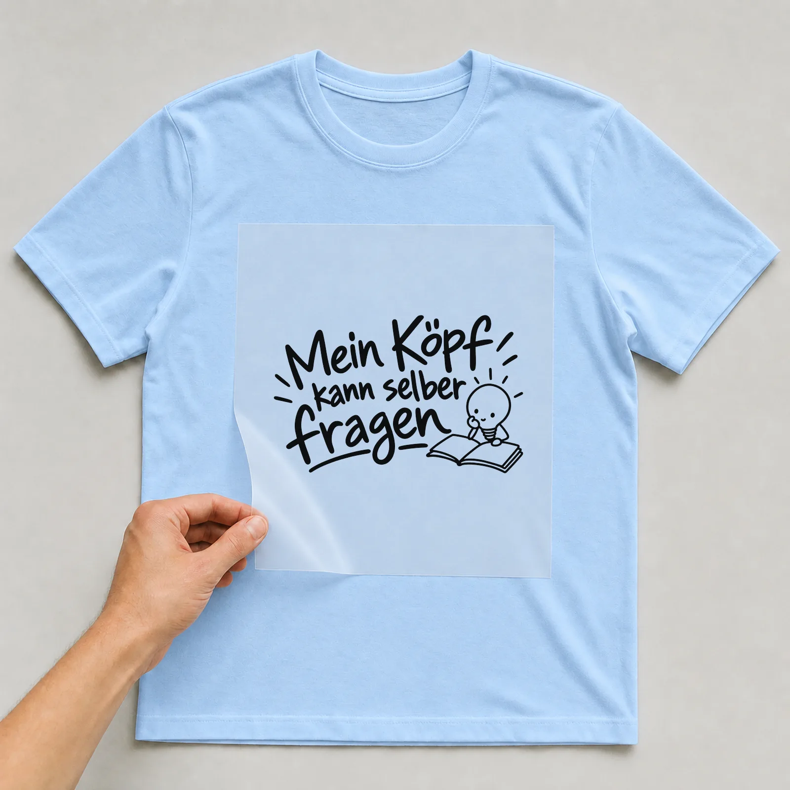 Bügelbild „Mein Kopf kann selber fragen“ auf hellblauem T-Shirt, Folie wird aufgelegt