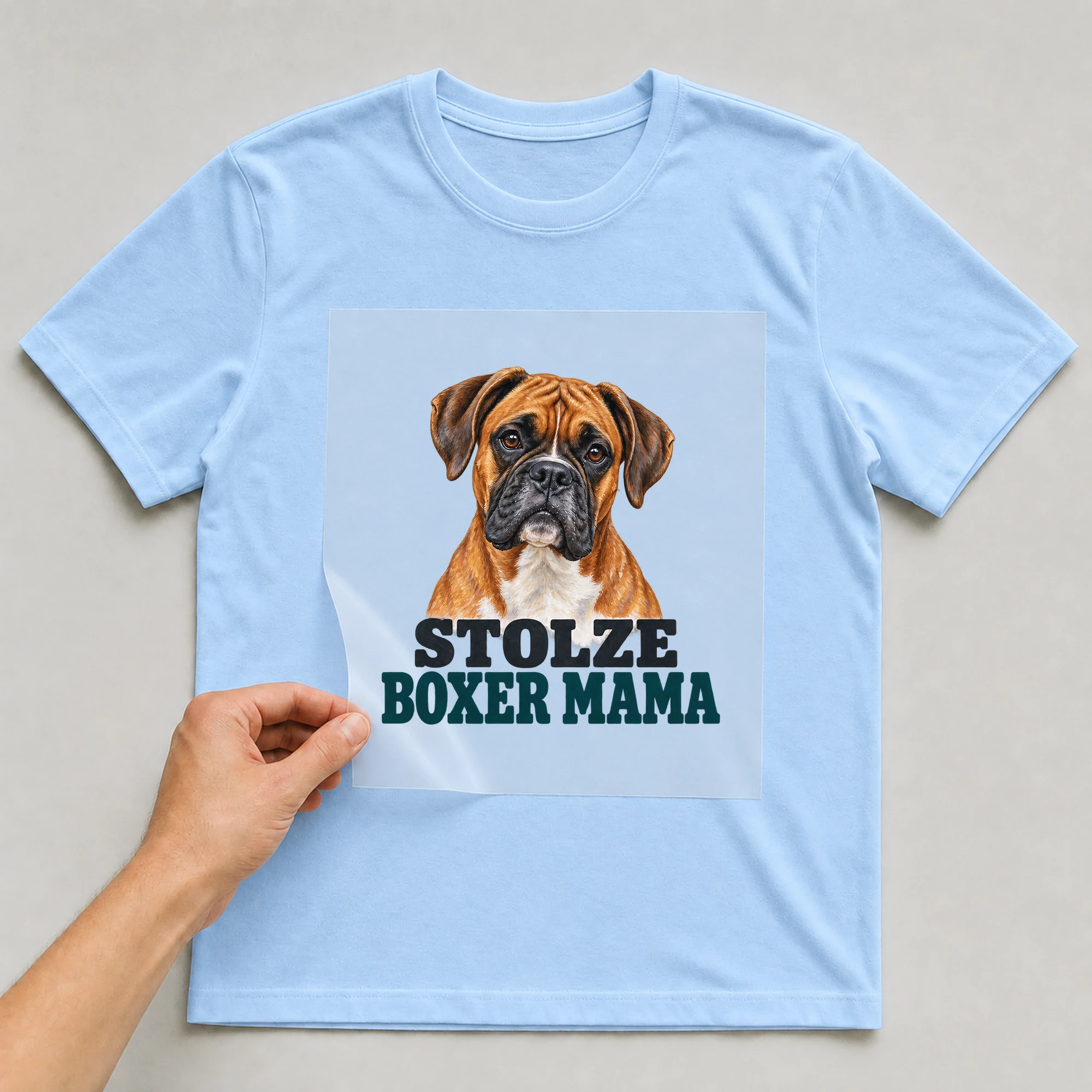 Bügelbild „Stolze Boxer Mama“ auf babyblauem T-Shirt, Folie wird aufgelegt
