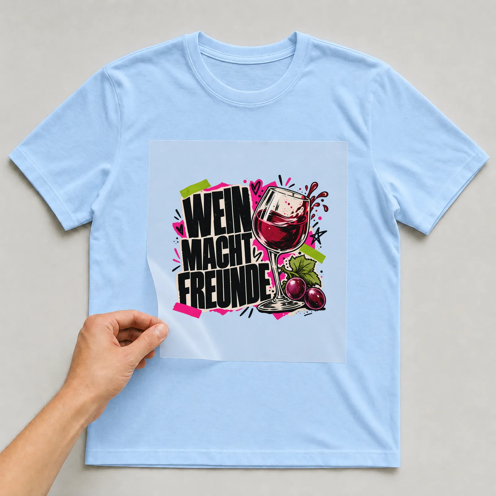 Bügelbild „Wein macht Freunde“ auf hellblauem T-Shirt, Folie wird aufgelegt