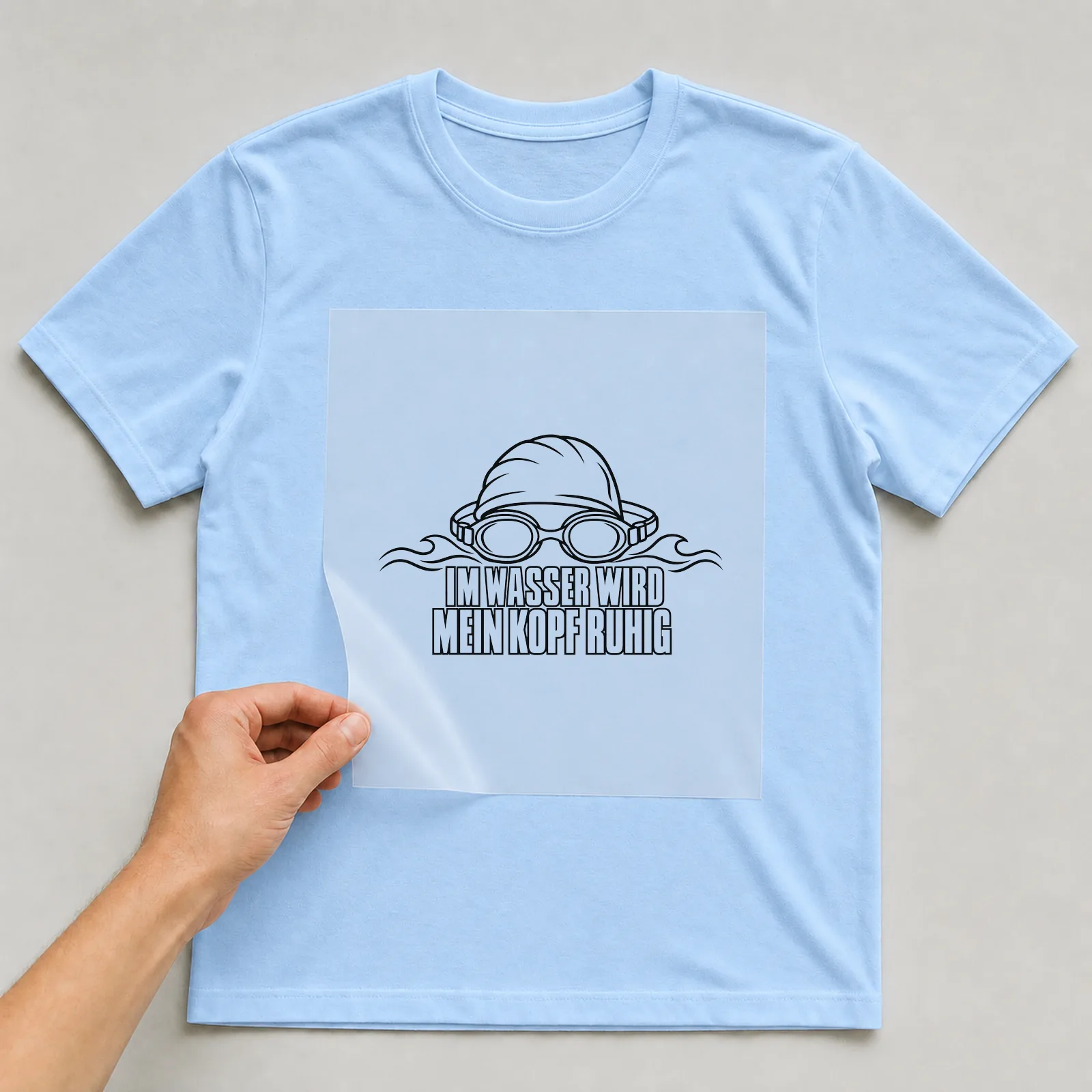 Bügelbild „Im Wasser wird mein Kopf ruhig“ auf hellblauem T-Shirt, Folie wird aufgelegt