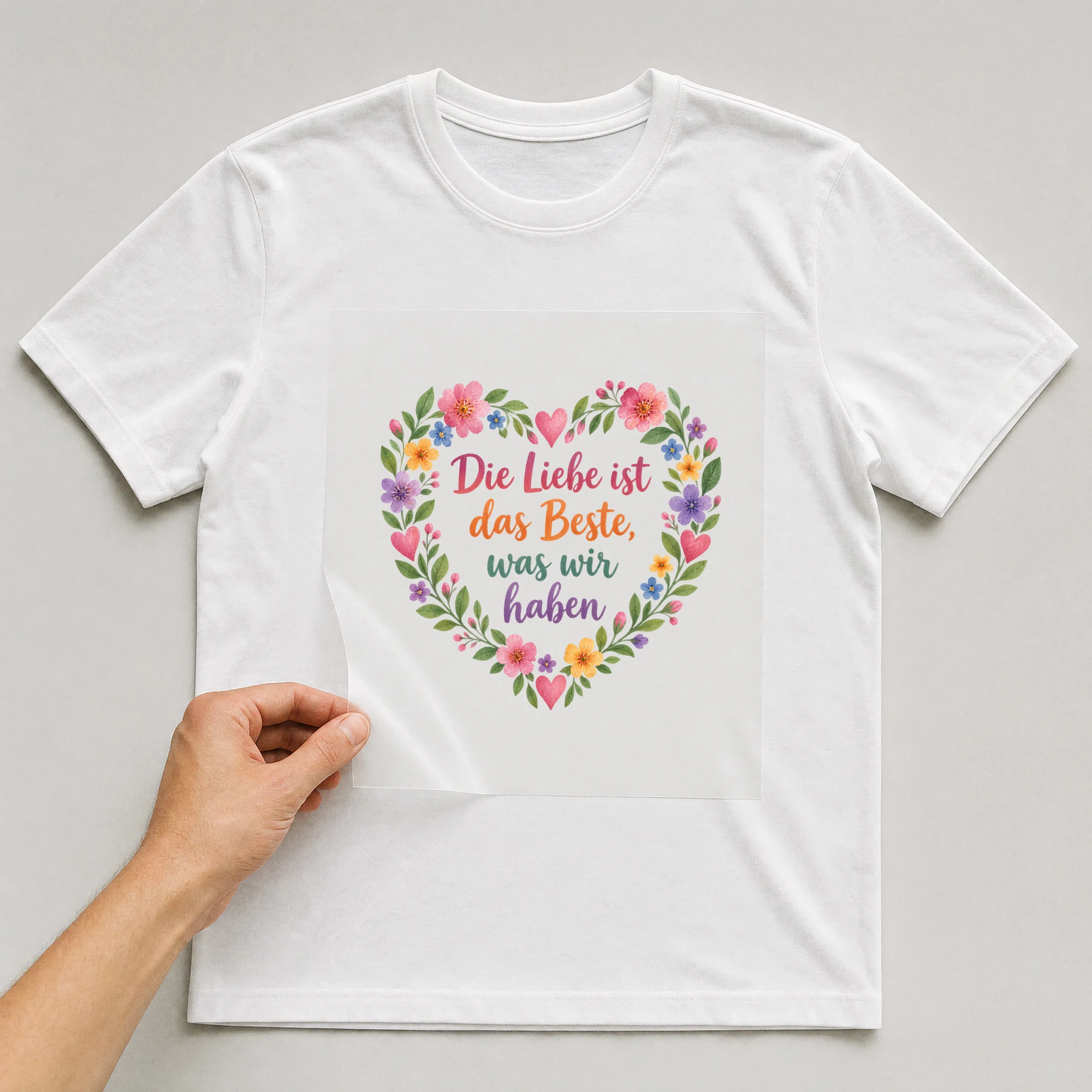 Bügelbild „Die Liebe ist das Beste, was wir haben“ auf weißem T-Shirt, Folie wird aufgelegt