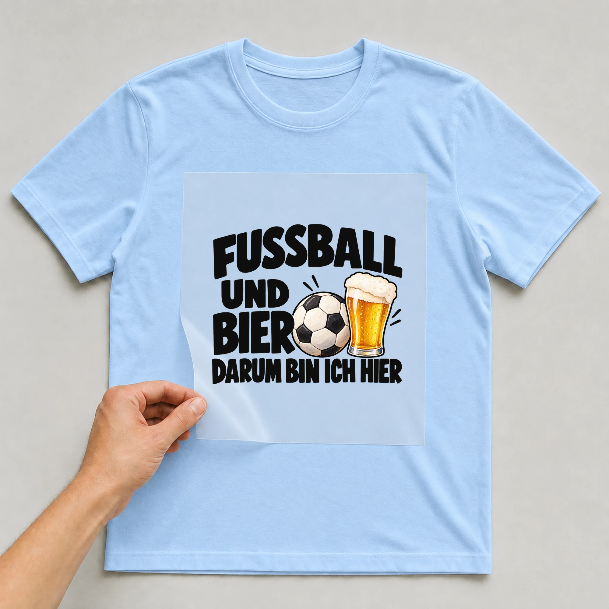 Bügelbild „Fußball und Bier darum bin ich hier“ auf babyblauem T-Shirt, Folie wird aufgelegt