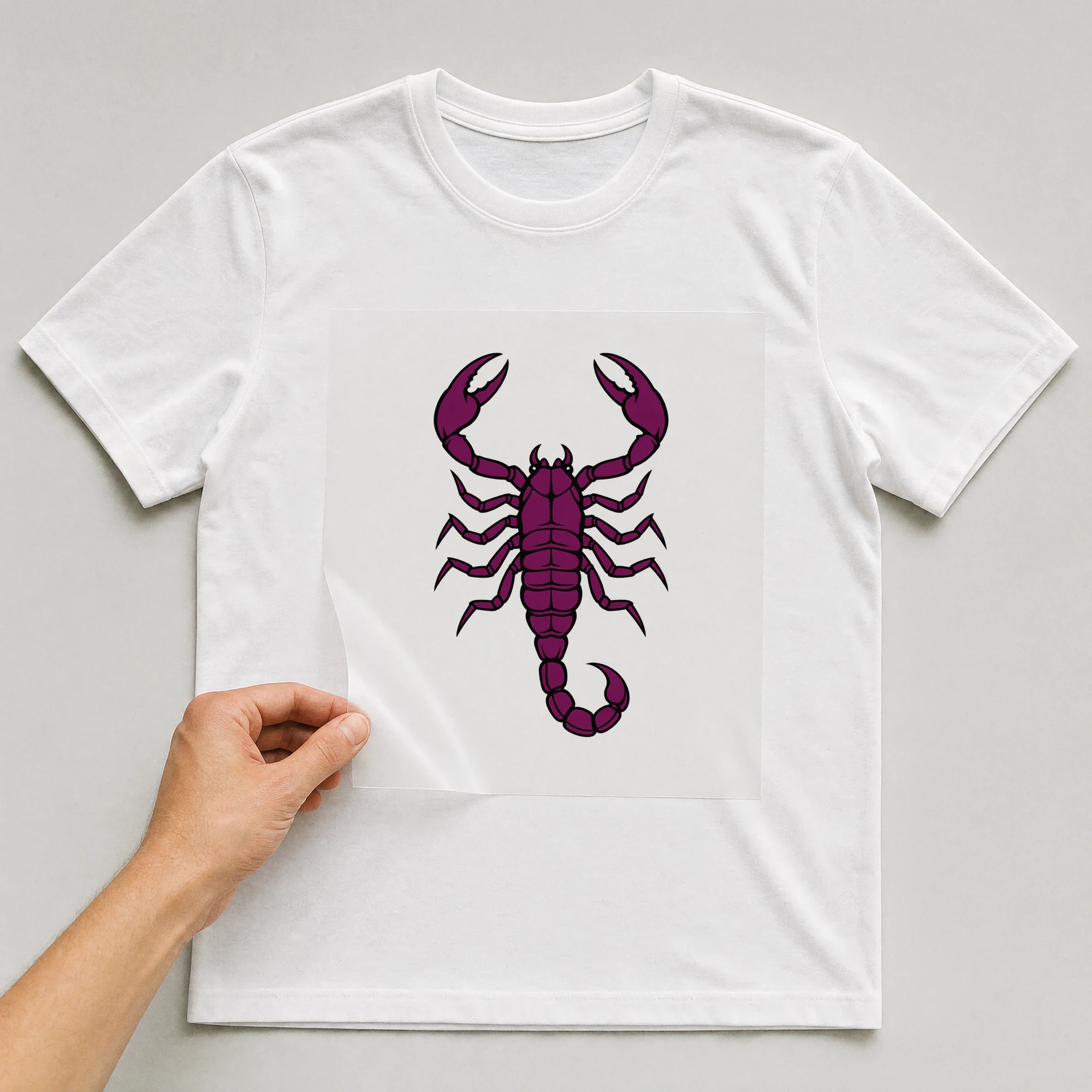 Bügelbild „Kritzel Stil Sternzeichen Skorpion“ auf weißem T-Shirt, Folie wird aufgelegt