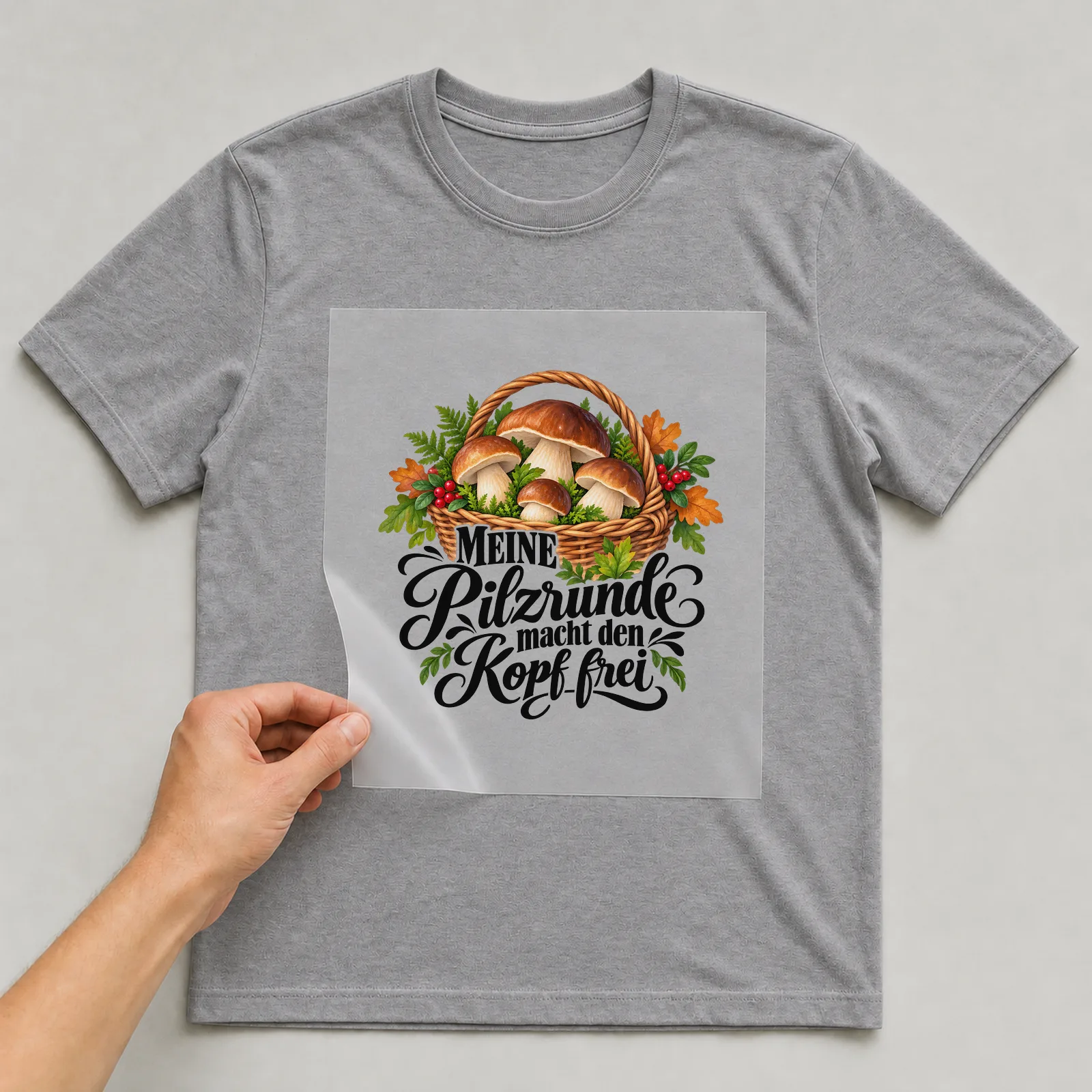 Bügelbild „MEINE Pilzrunde macht den Kopf frei“ auf grauem T-Shirt, Folie wird aufgelegt