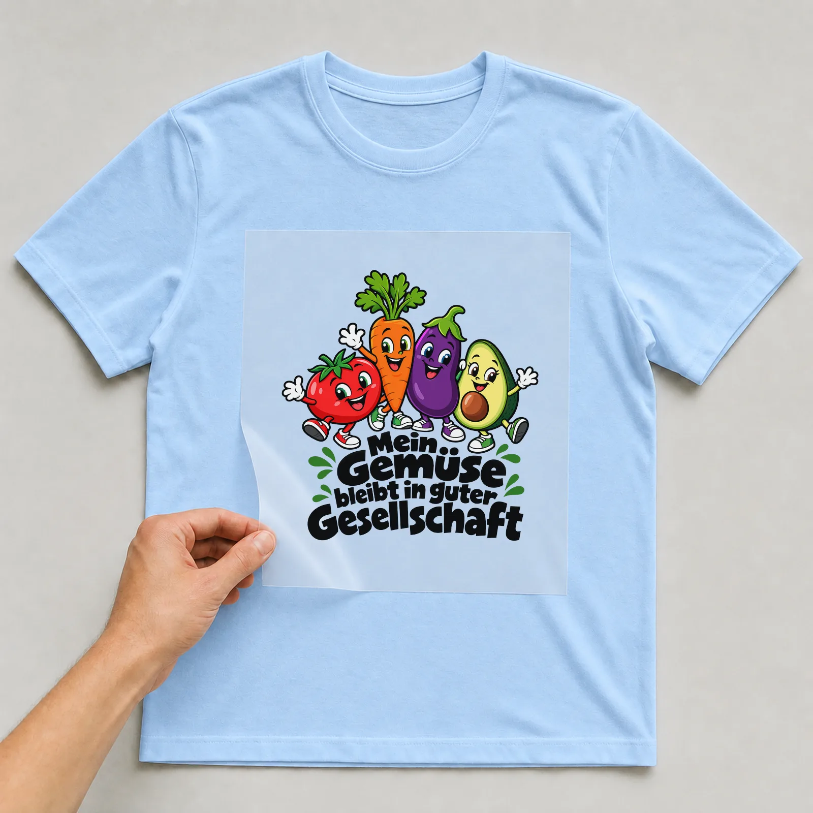 Bügelbild „Mein Gemüse bleibt in guter Gesellschaft“ auf hellblauem T-Shirt, Folie wird aufgelegt