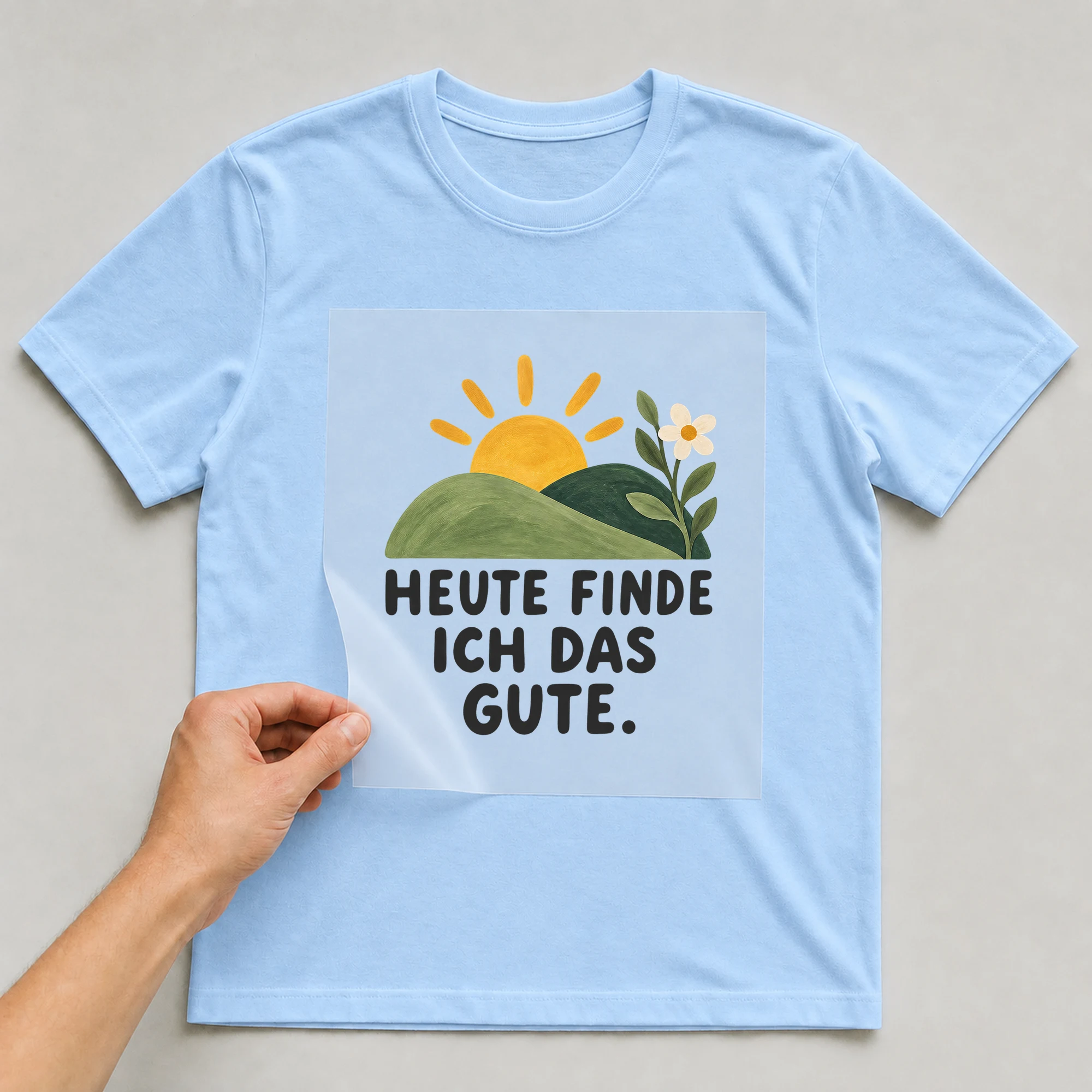 Bügelbild „HEUTE FINDE ICH DAS GUTE.“ auf babyblauem T-Shirt, Folie wird aufgelegt