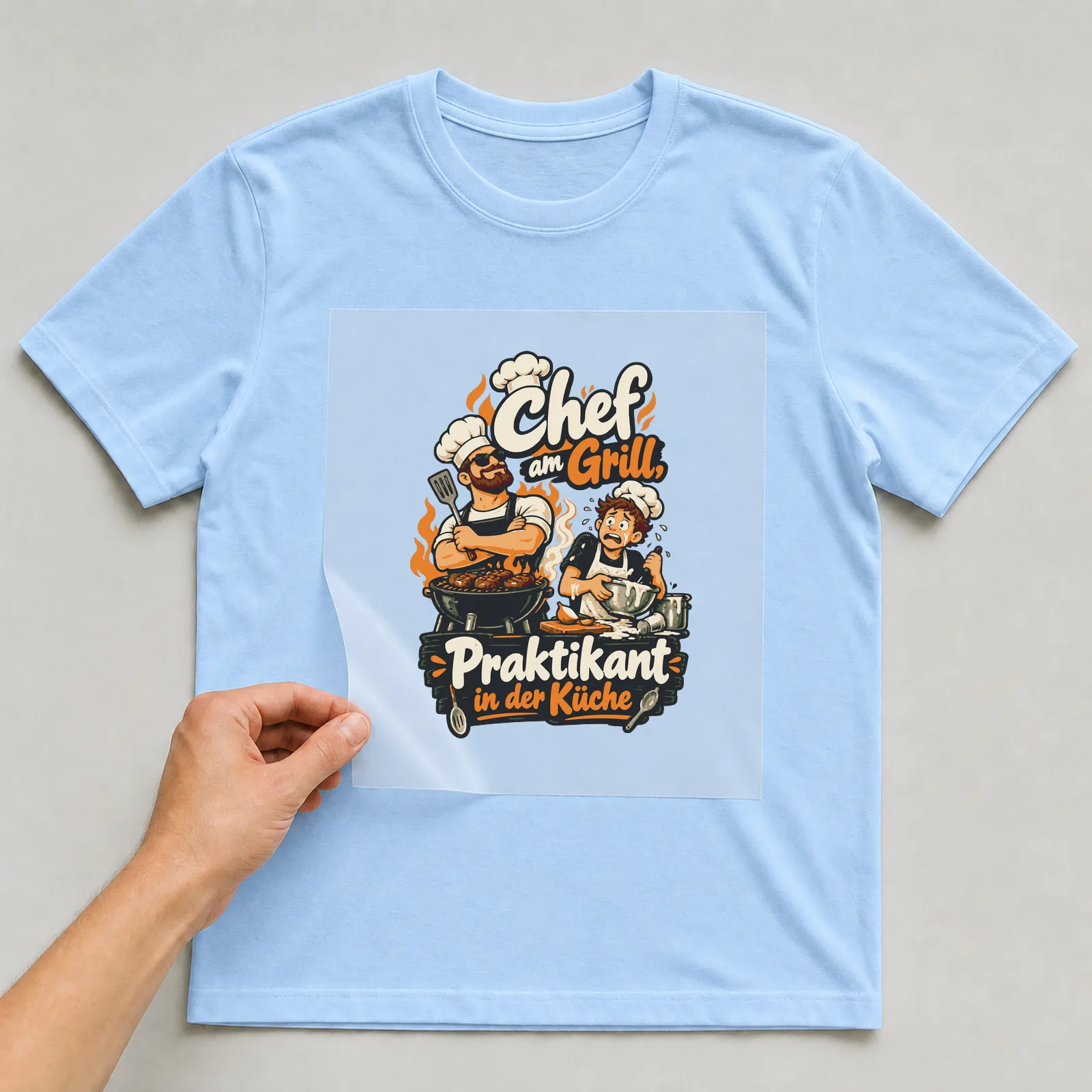 Bügelbild Chef am Grill, Praktikant in der Küche auf hellblauem T-Shirt, Folie wird aufgelegt