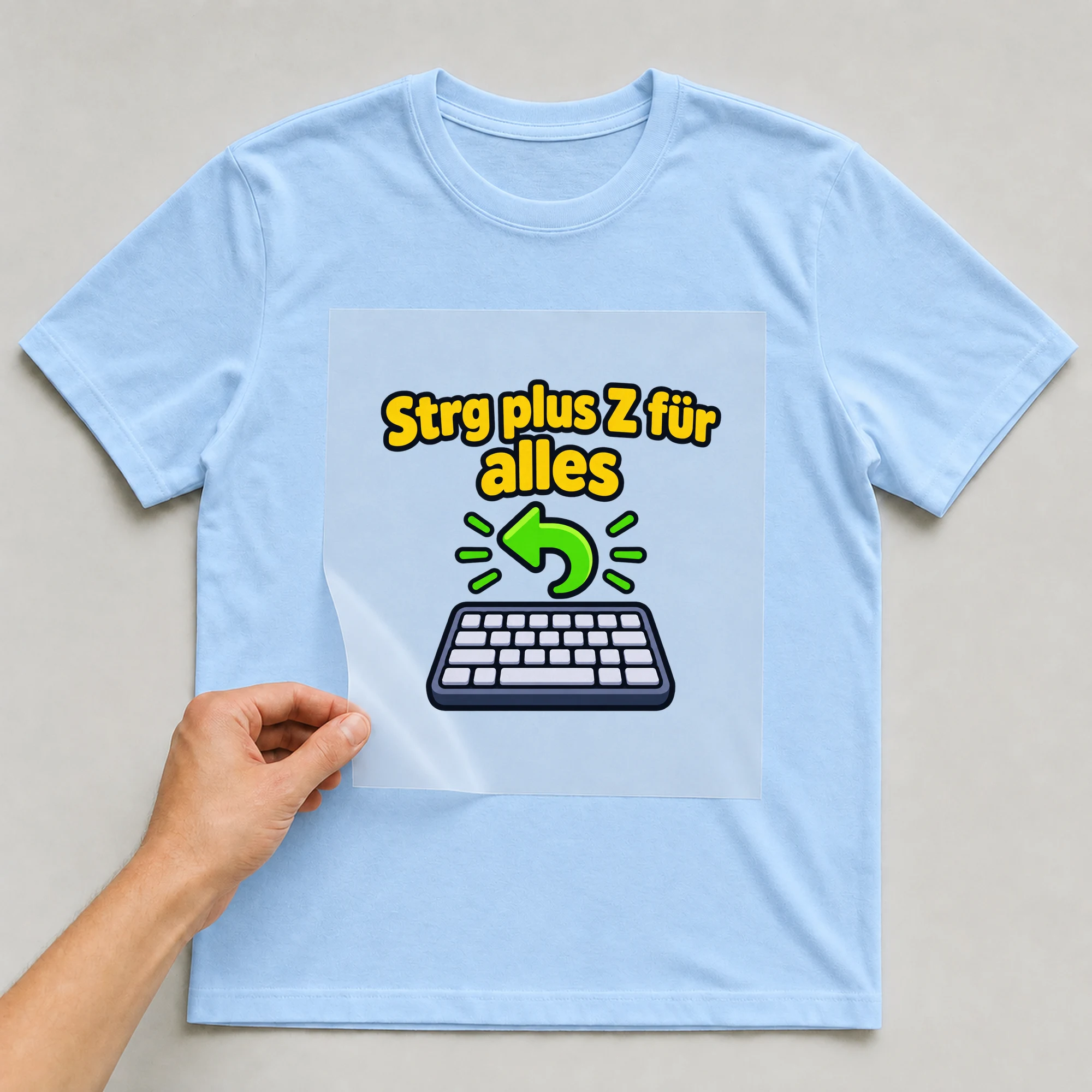 Bügelbild „Strg plus Z für alles“ auf babyblauem T-Shirt, Folie wird aufgelegt