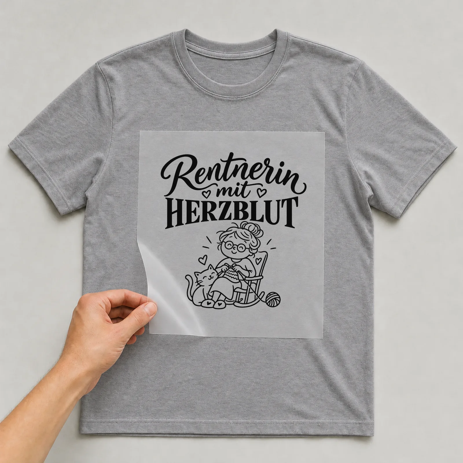 Bügelbild „Rentnerin mit Herzblut“ auf grauem T-Shirt, Folie wird aufgelegt
