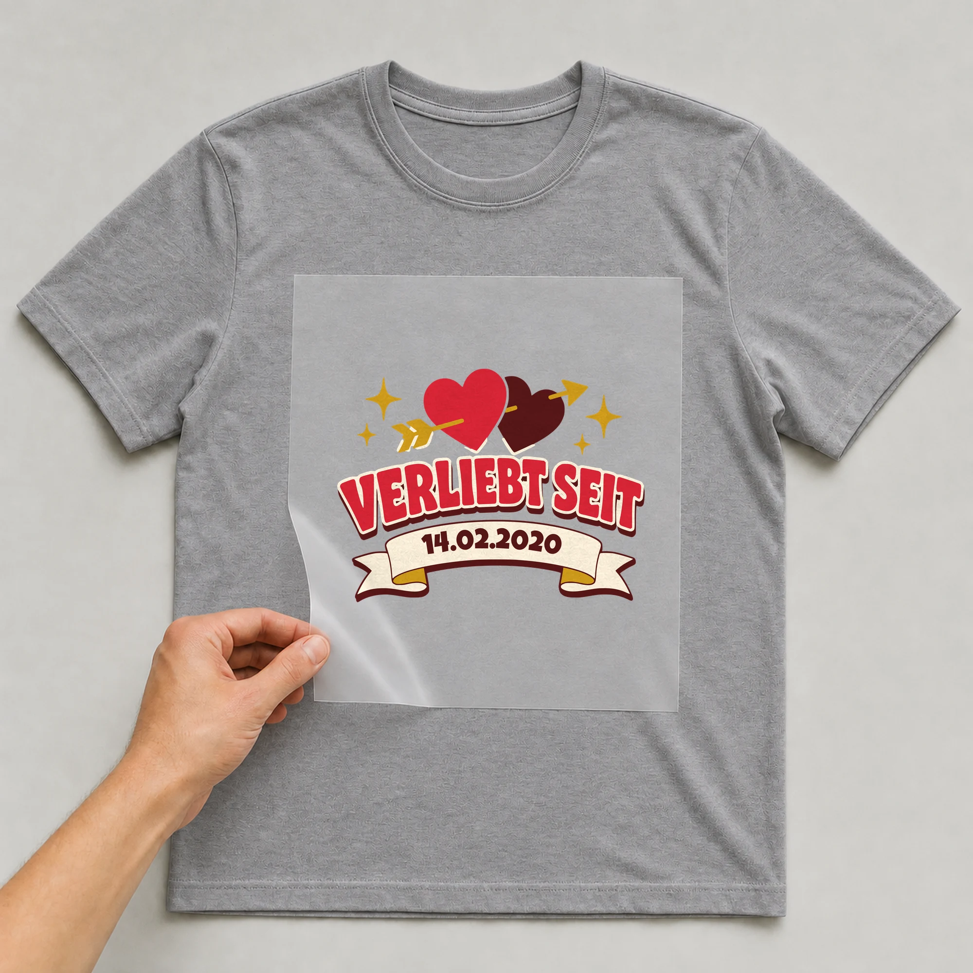 Bügelbild Verliebt mit Datum auf grauem T-Shirt, Folie wird aufgelegt
