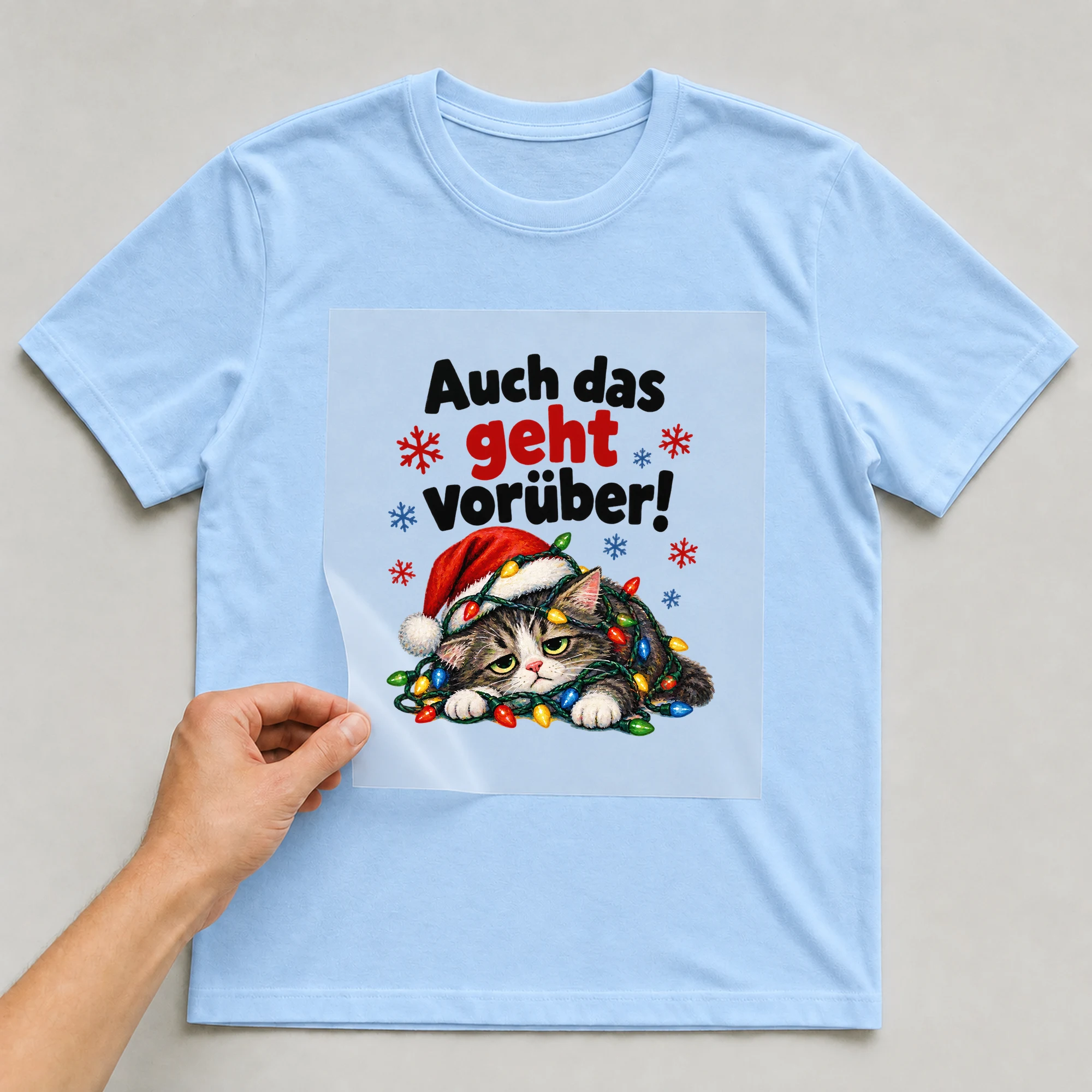 Bügelbild „Auch das geht vorüber!“ auf babyblauem T-Shirt, Folie wird aufgelegt