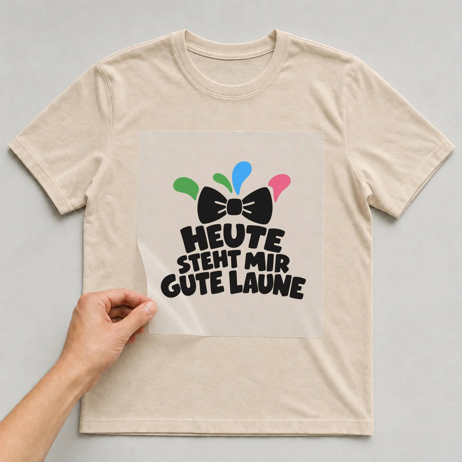 Bügelbild „Heute steht mir gute Laune“ auf beigem T-Shirt, Folie wird aufgelegt