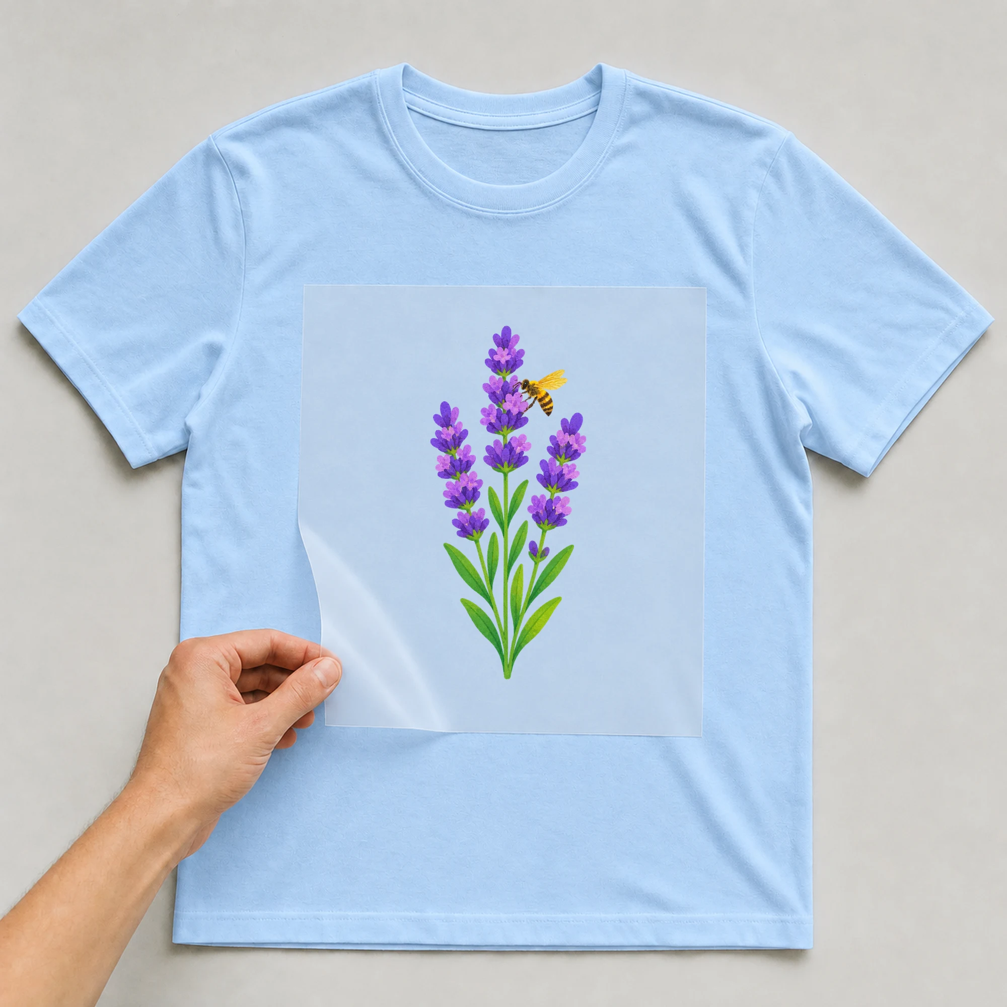 Bügelbild „Lavendel mit Biene“ auf babyblauem T-Shirt, Folie wird aufgelegt