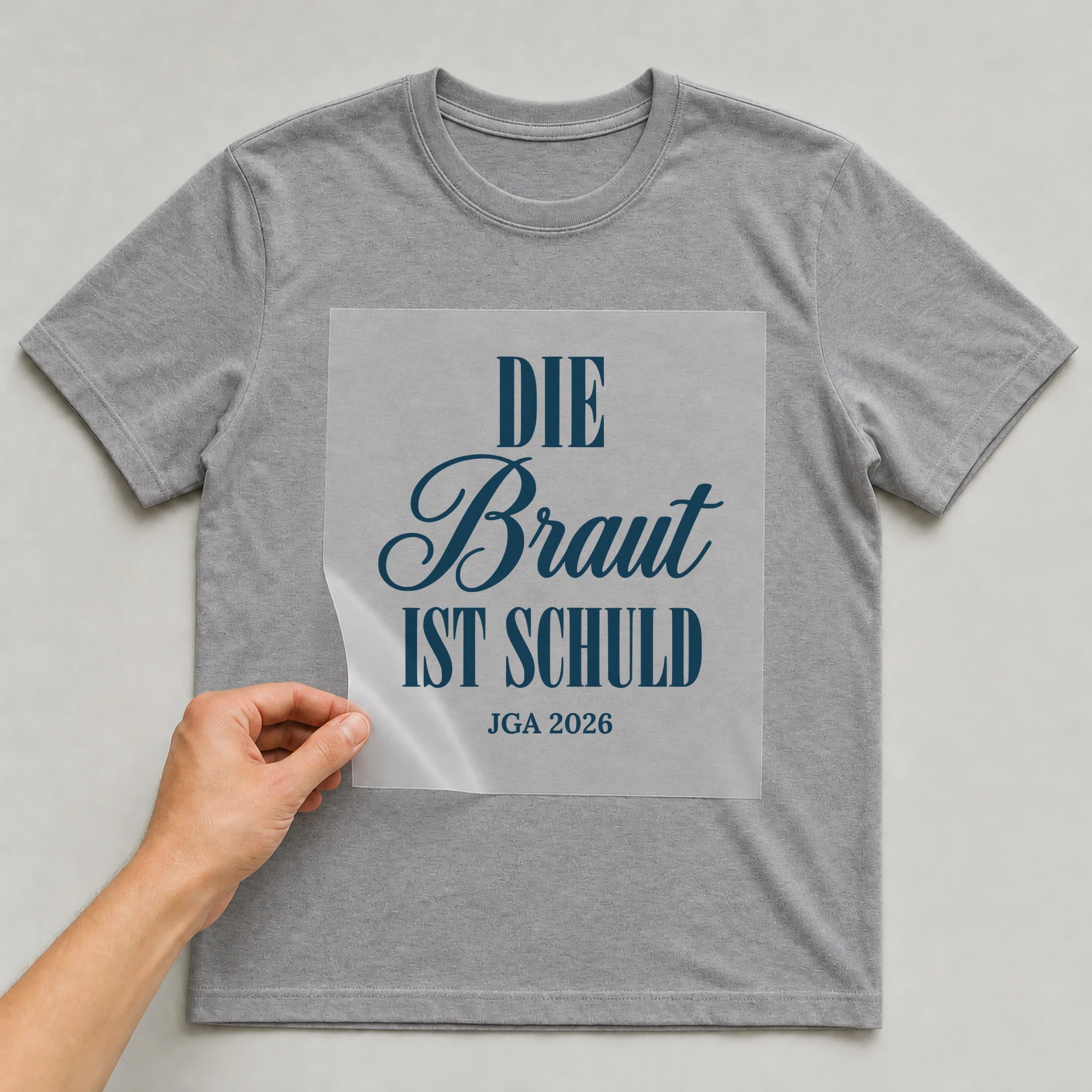 Bügelbild Die Braut ist schuld auf grauem T-Shirt, Folie wird aufgelegt