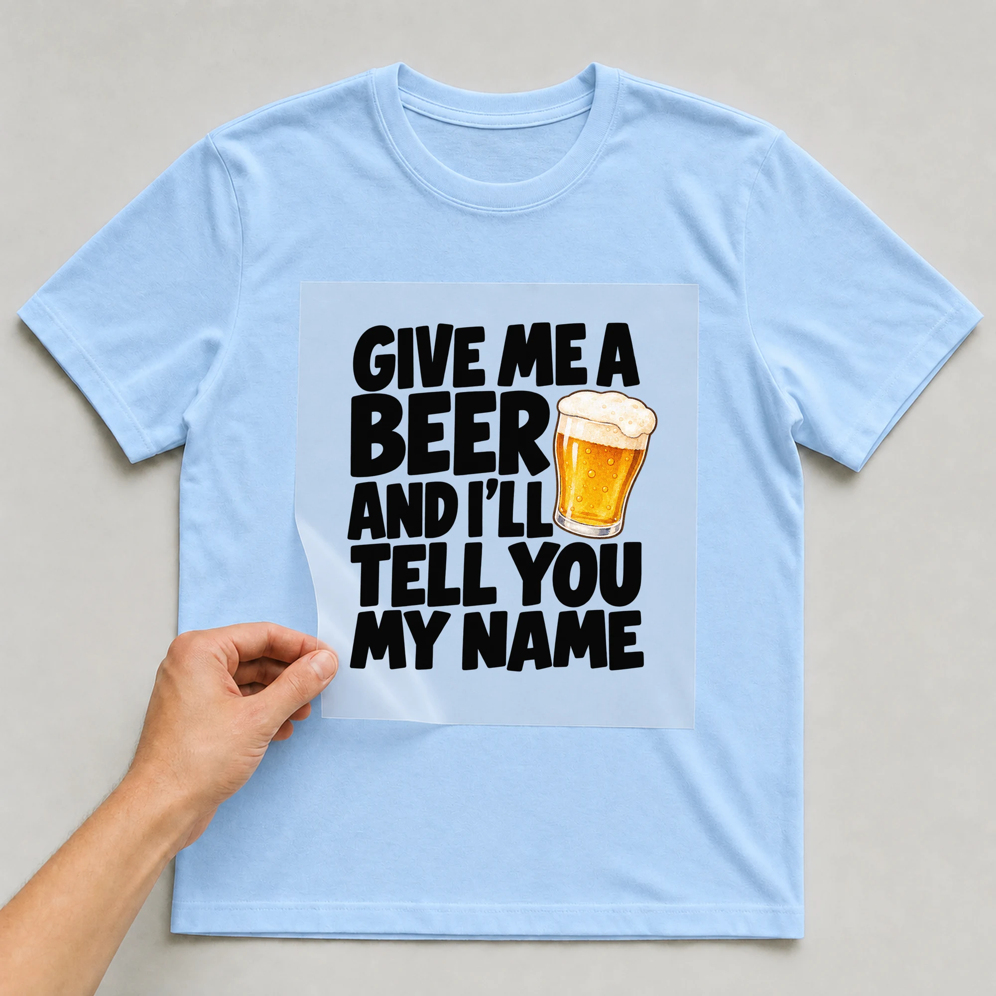 Bügelbild „Give Me A Beer And I'll Tell You My Name“ auf babyblauem T-Shirt, Folie wird aufgelegt