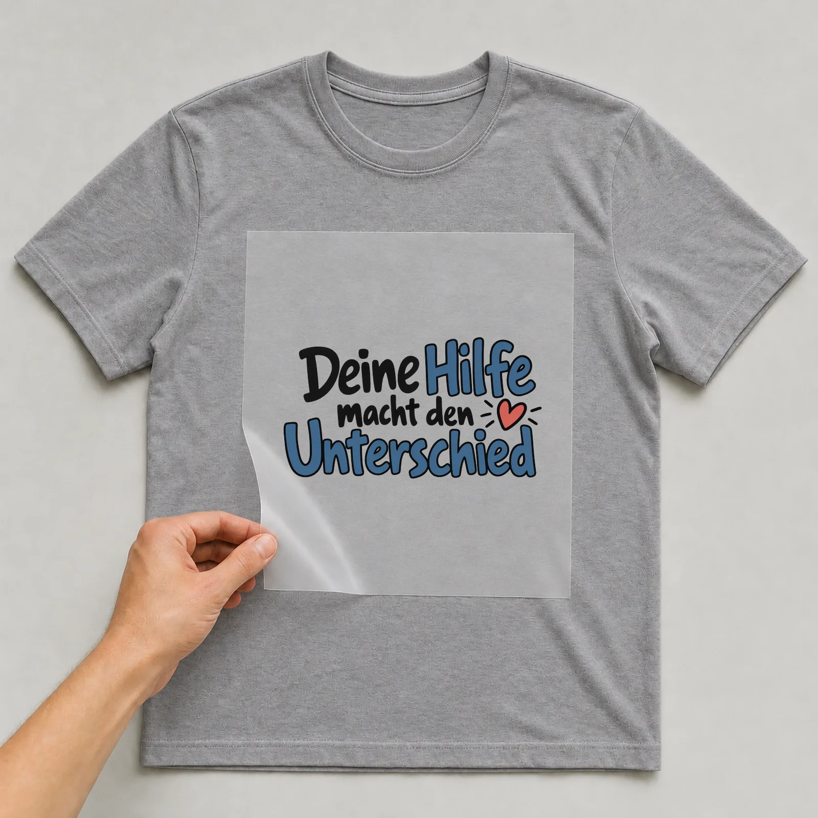 Bügelbild „Deine Hilfe macht den Unterschied“ auf grauem T-Shirt, Folie wird aufgelegt