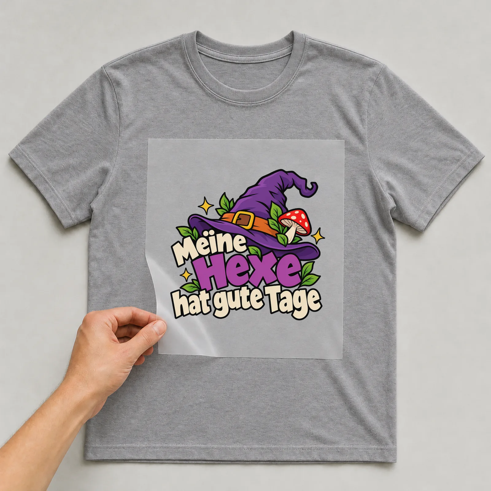 Bügelbild „Meine Hexe hat gute Tage“ auf grauem T-Shirt, Folie wird aufgelegt