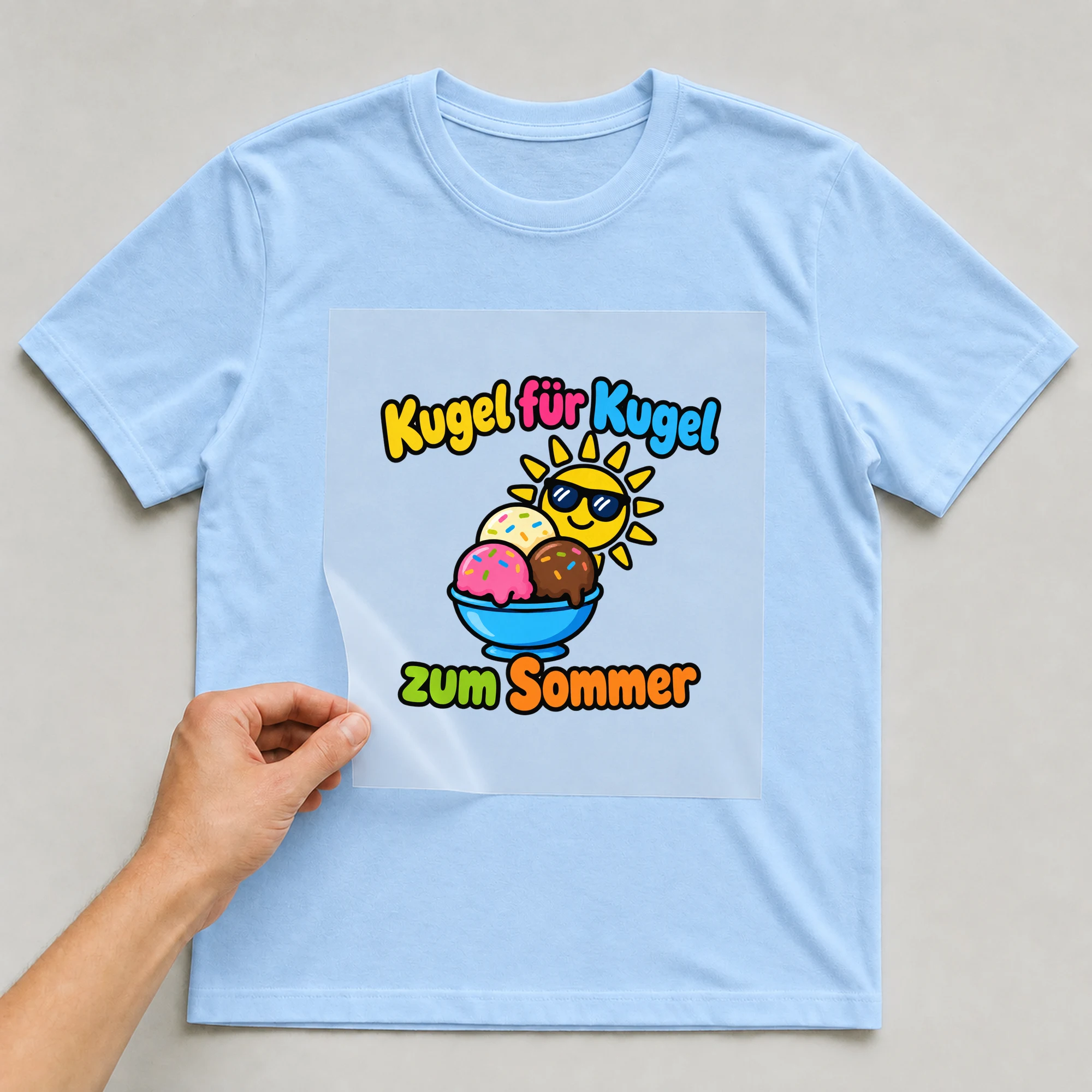 Bügelbild „Kugel für Kugel zum Sommer“ auf babyblauem T-Shirt, Folie wird aufgelegt