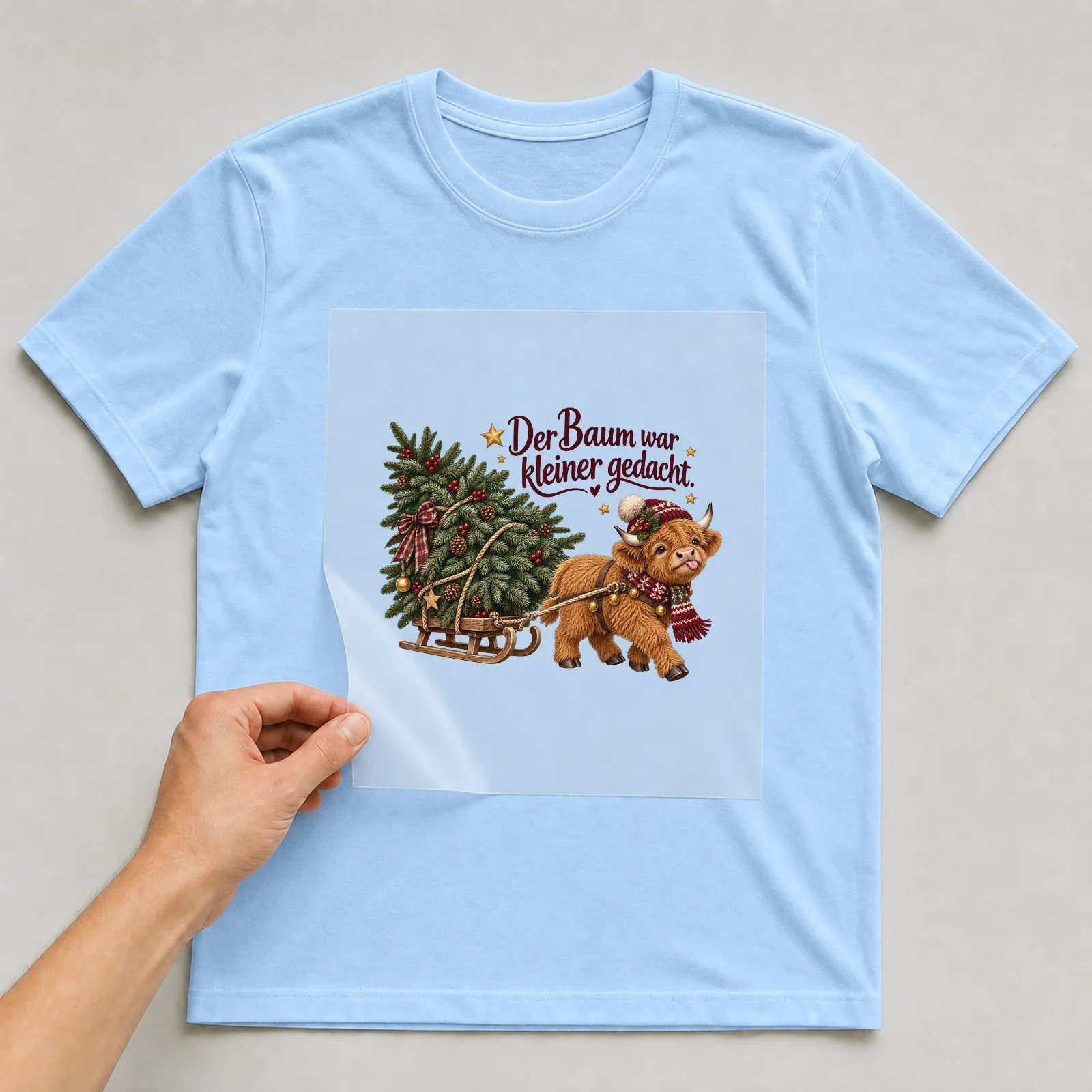 Bügelbild Der Baum war kleiner gedacht. auf hellblauem T-Shirt, Folie wird aufgelegt