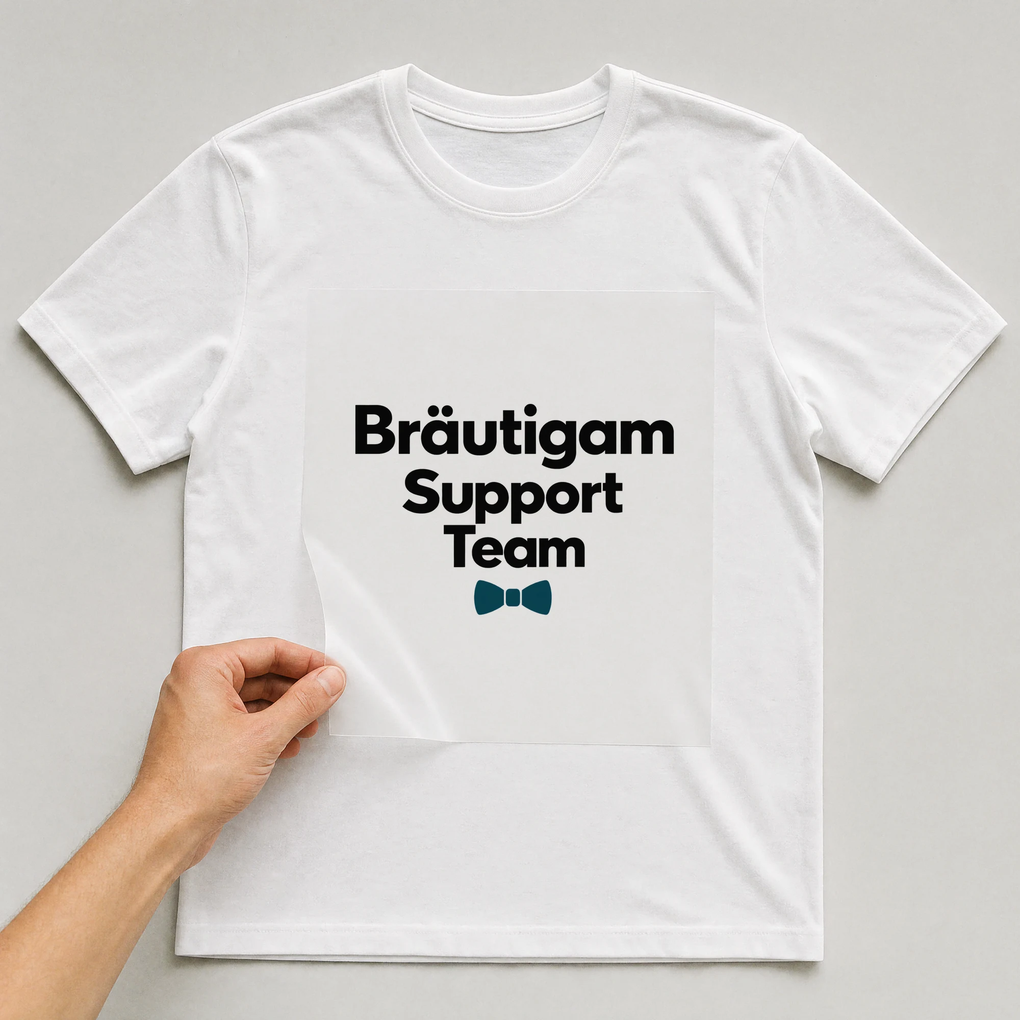 Bügelbild „Bräutigam Support Team“ auf weißem T-Shirt, Folie wird aufgelegt