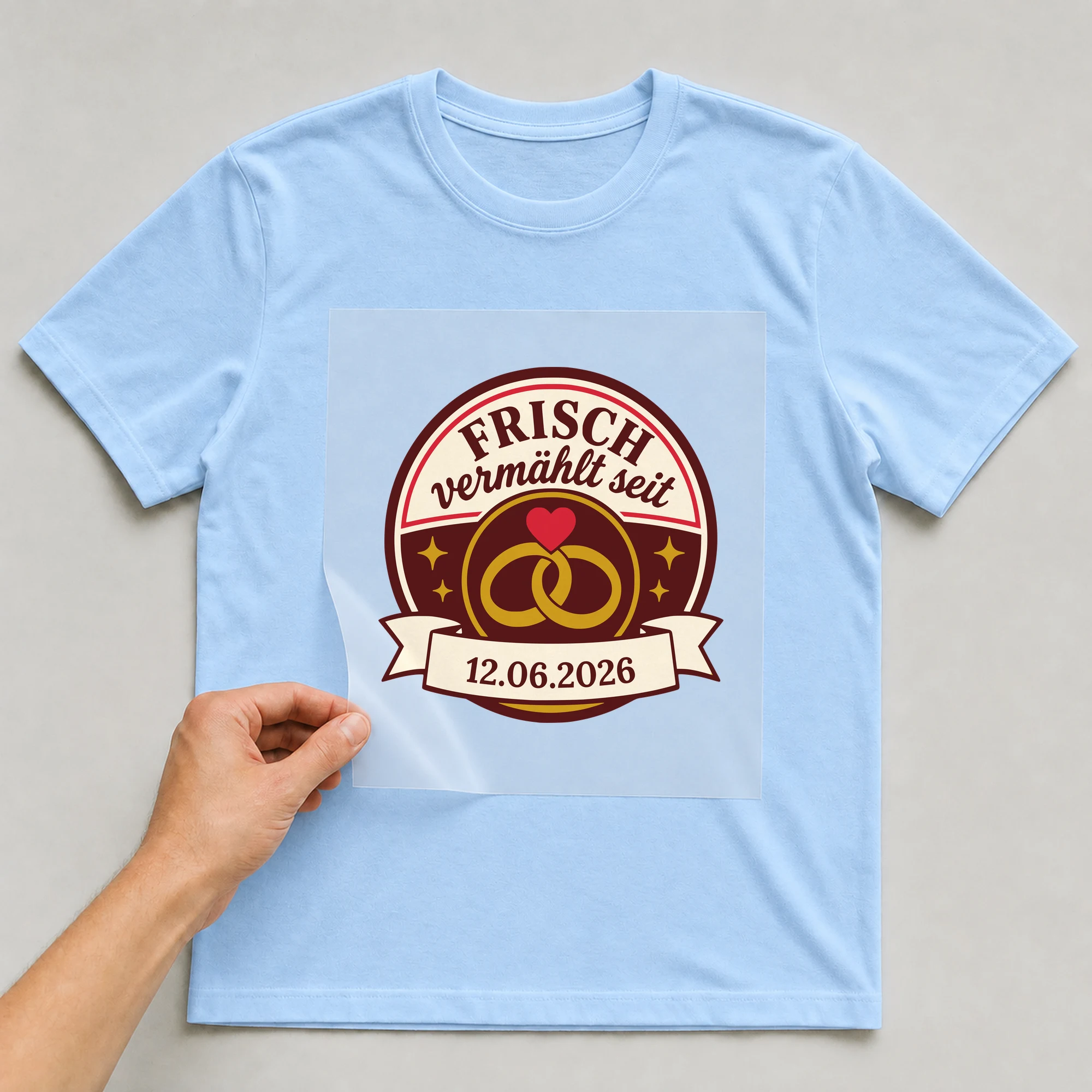 Bügelbild Frisch vermählt mit Datum auf hellblauem T-Shirt, Folie wird aufgelegt